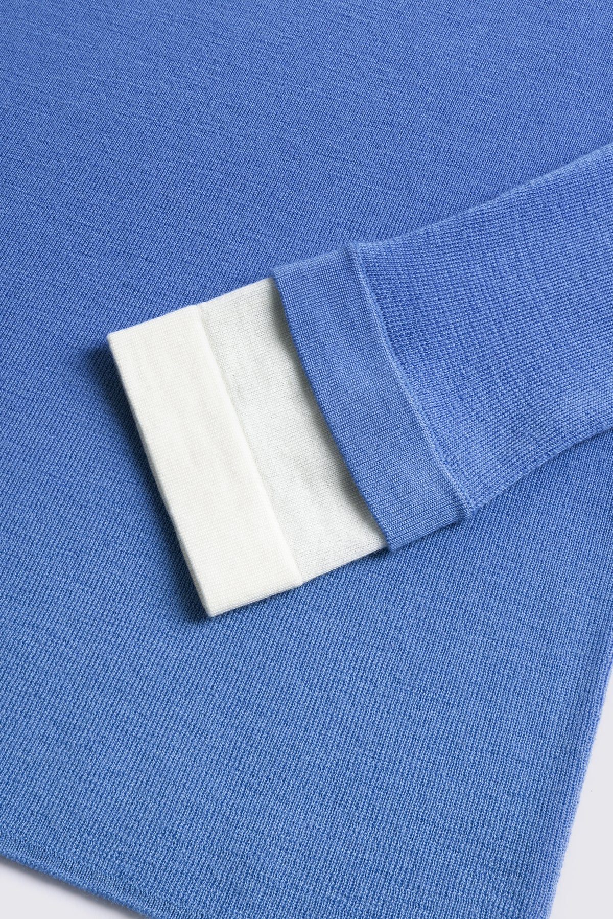 Sky blue merino crew neck jumper with an ivory cuff, shown flat