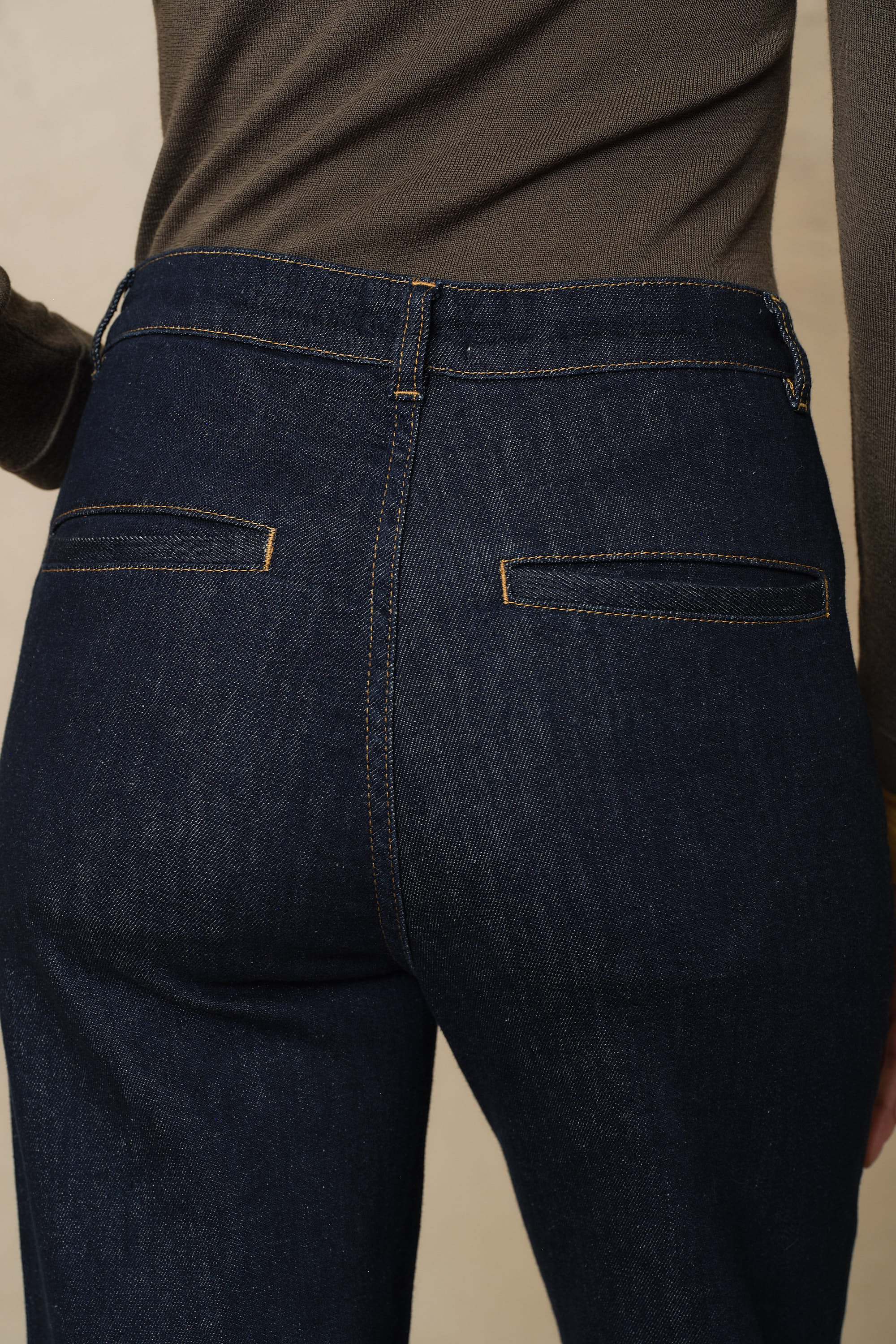Close back detail of the dark rinse wide leg jeans, showing the high waistband and welt pockets