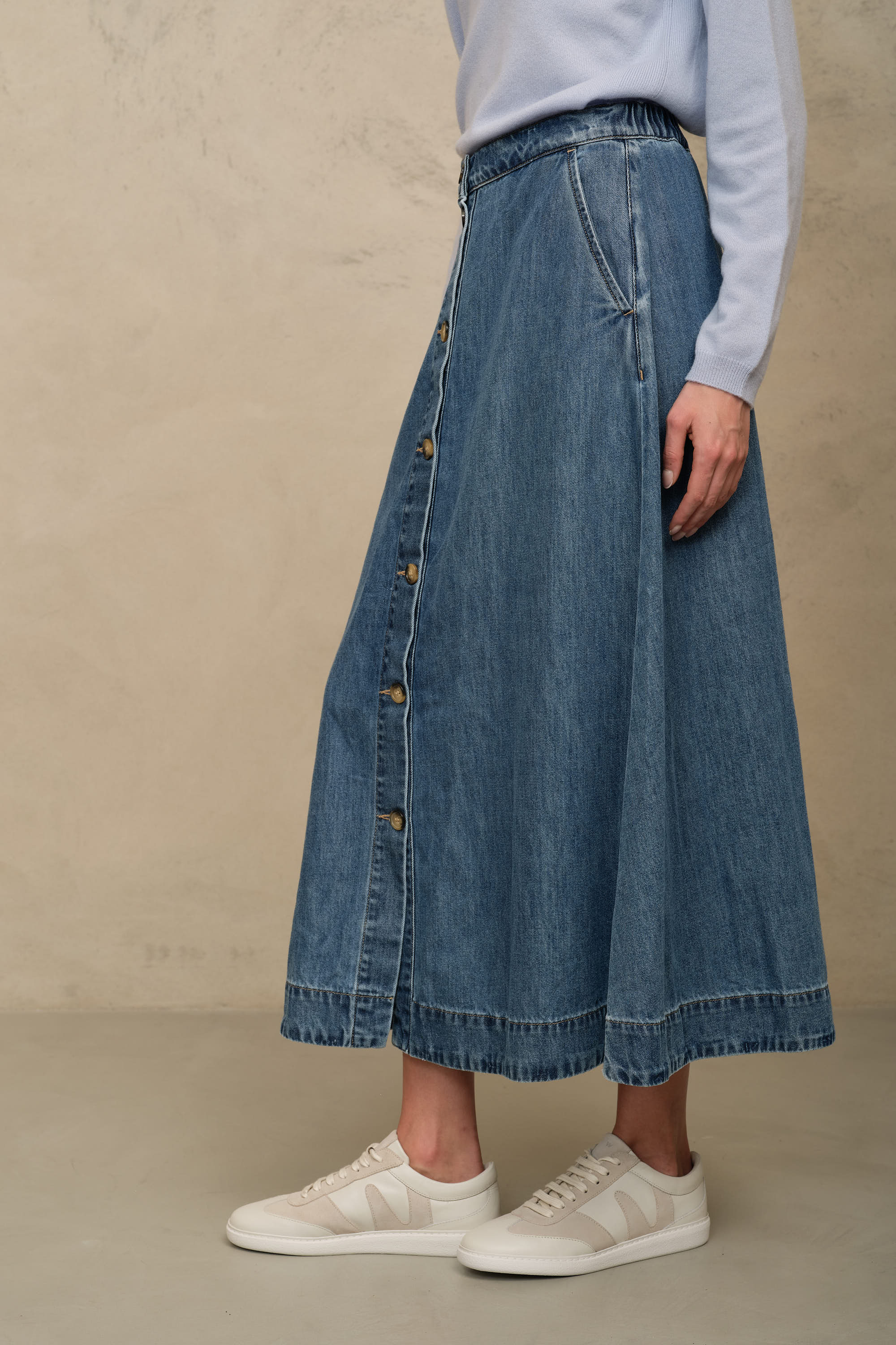 Imogen mid wash denim skirt showing the flat waistband and button through front, side view