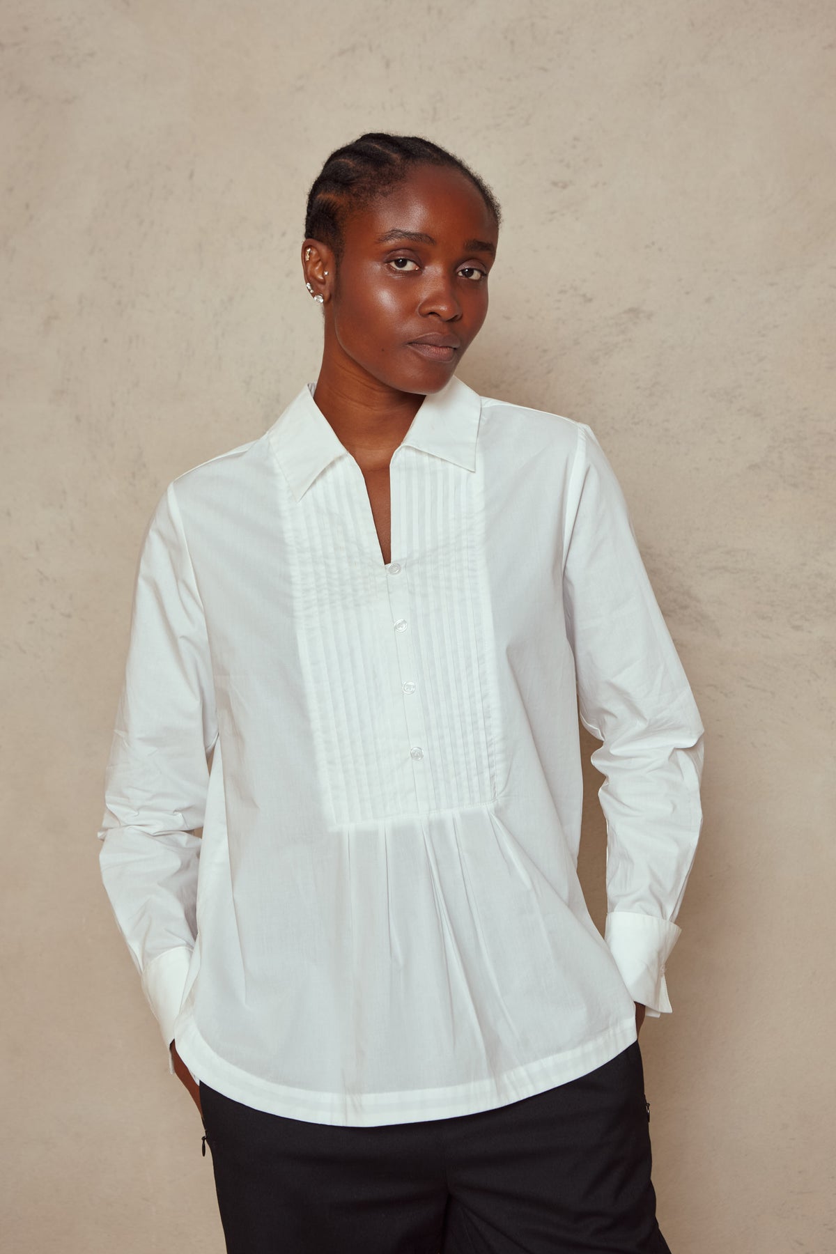 Model wearing the Etta bib shirt in ivory, worn loose with black trousers, front view