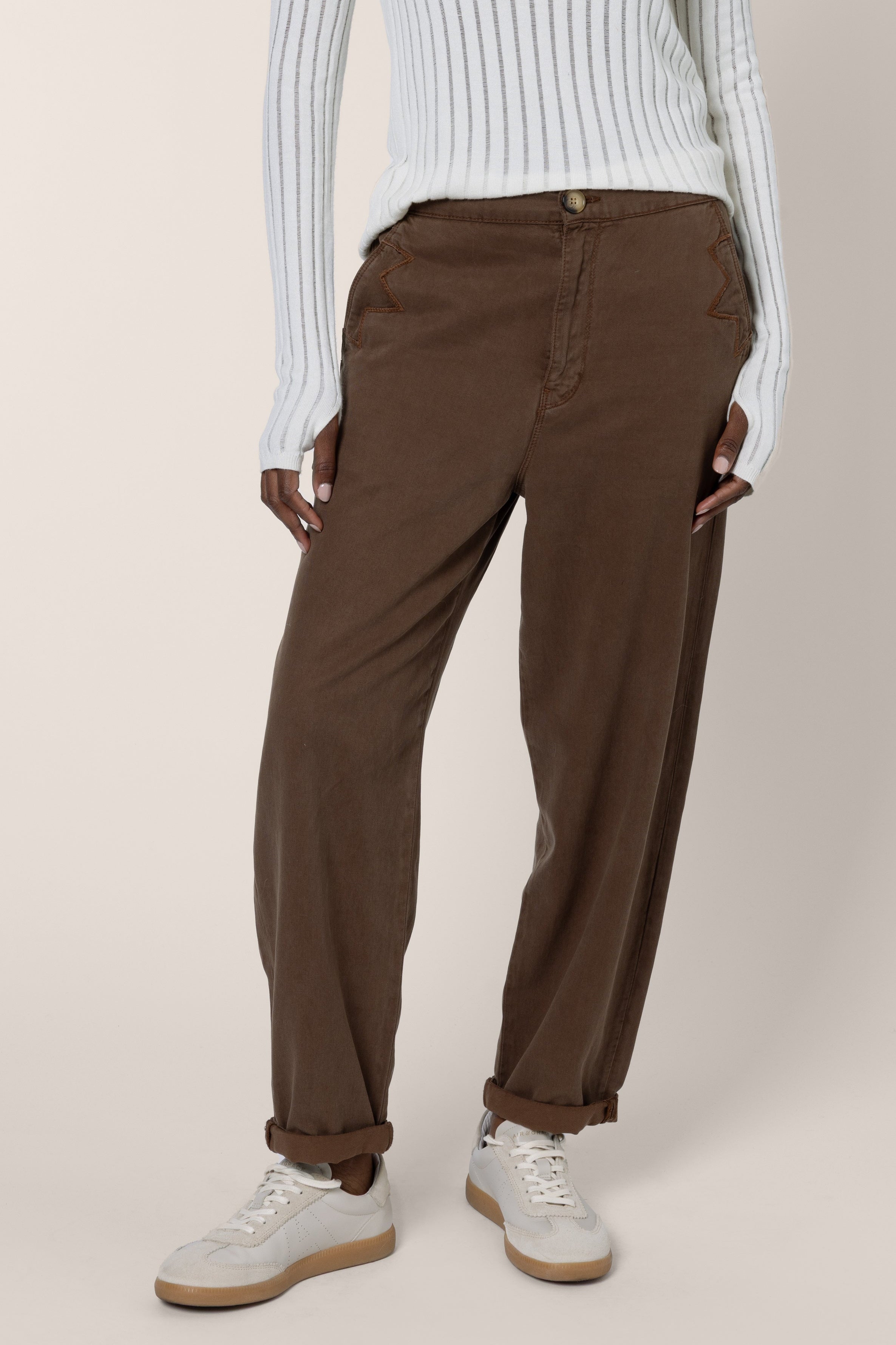 model wearing brown cargo trousers and ivory jumper on a white background