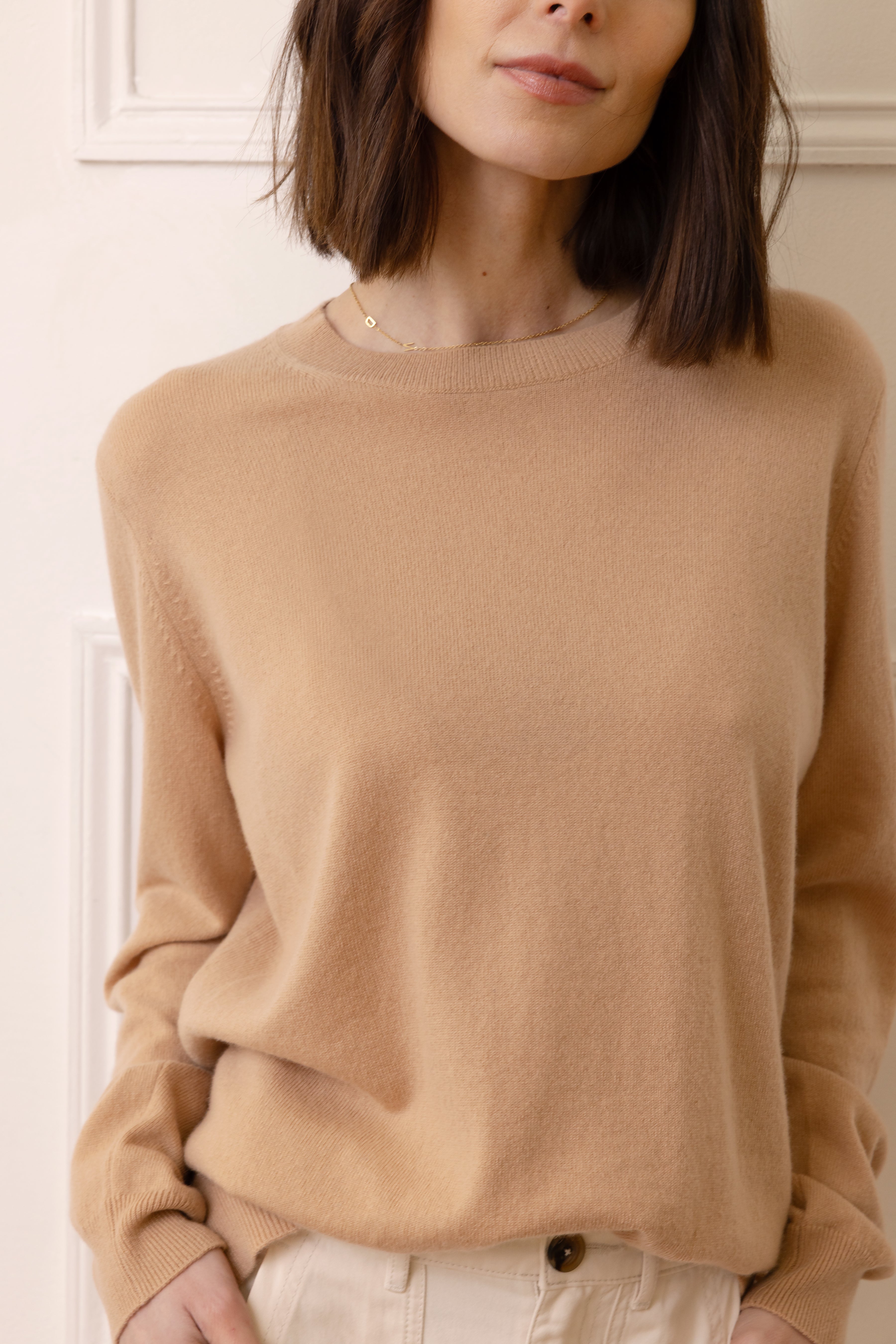 Person wearing a beige sweater against a neutral background