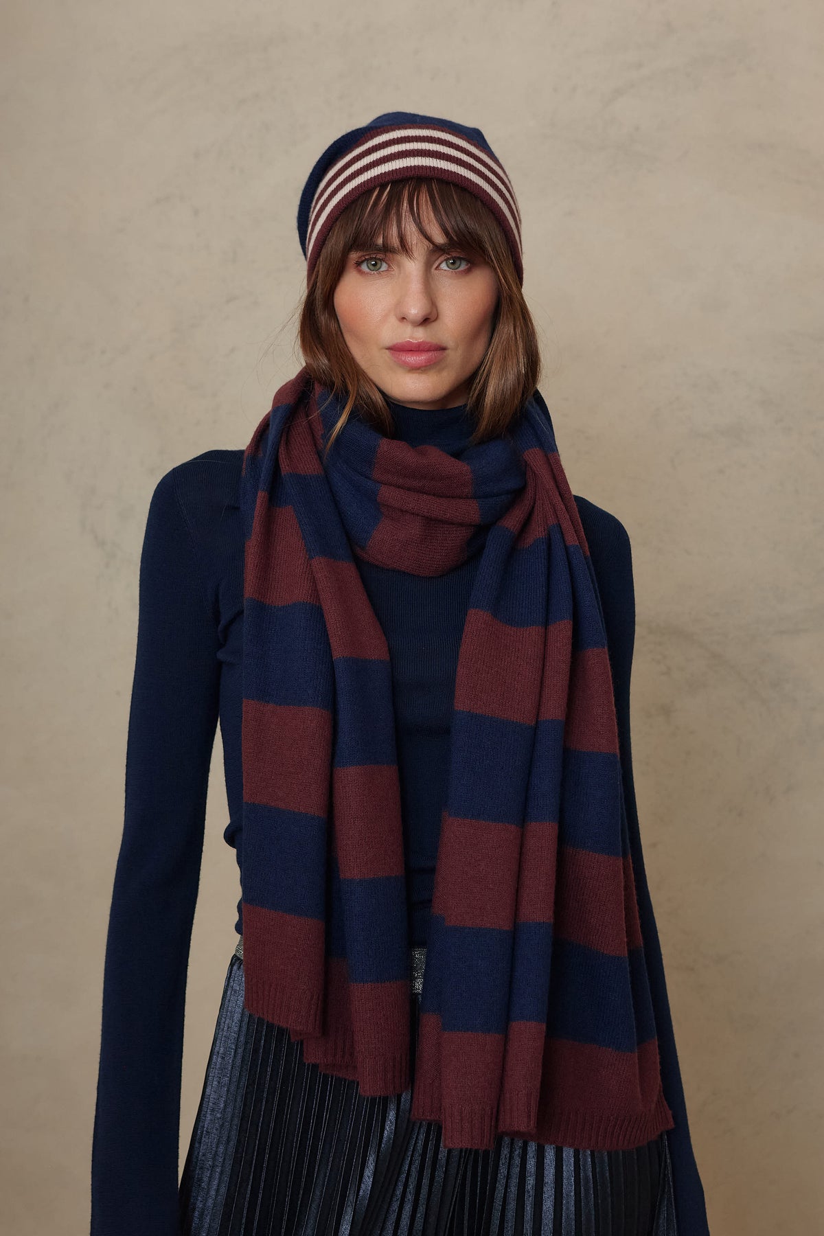Model wearing the Carmel cashmere blend scarf in navy and burgundy stripes with the Zinnie beanie in navy, front view