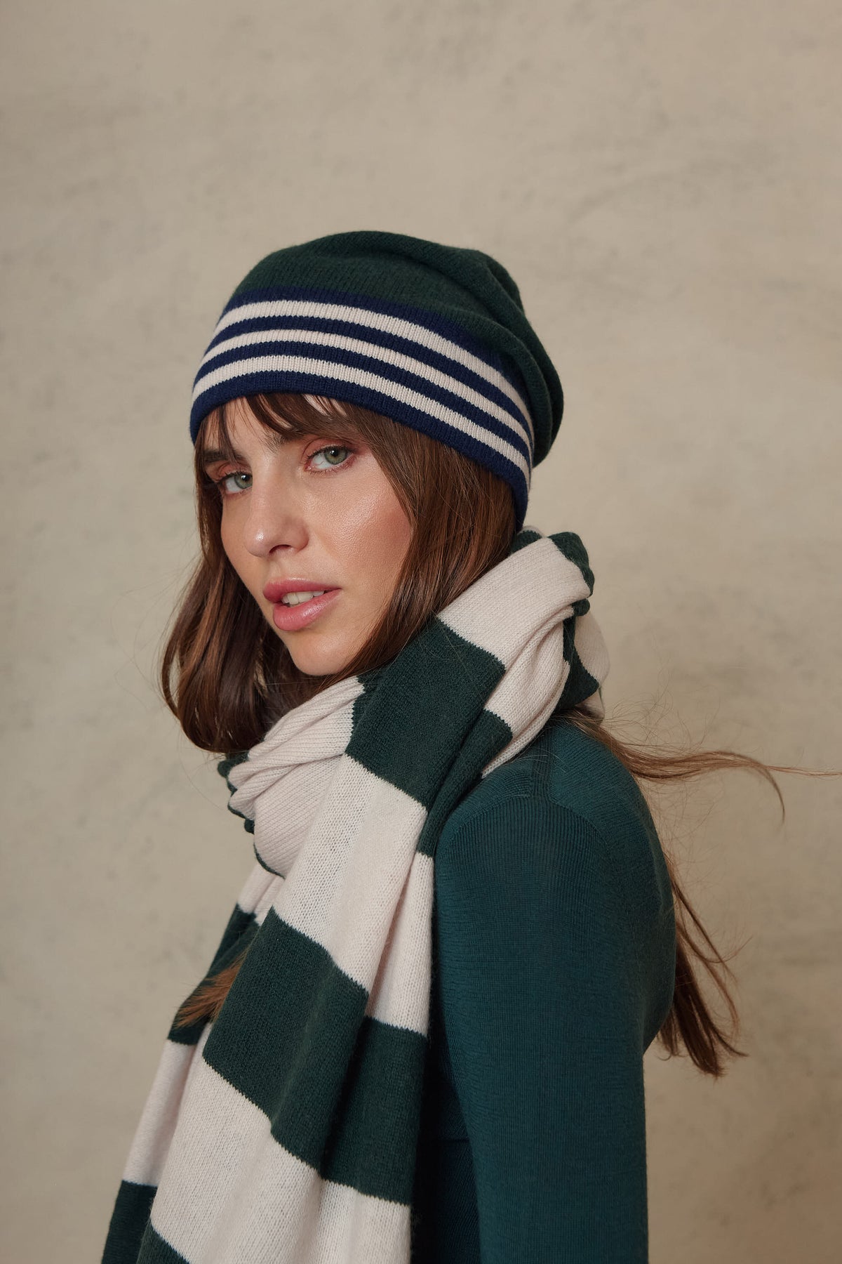 Zinnie cashmere blend beanie in bottle green worn with the Carmel cashmere blend scarf in soft stone and bottle green