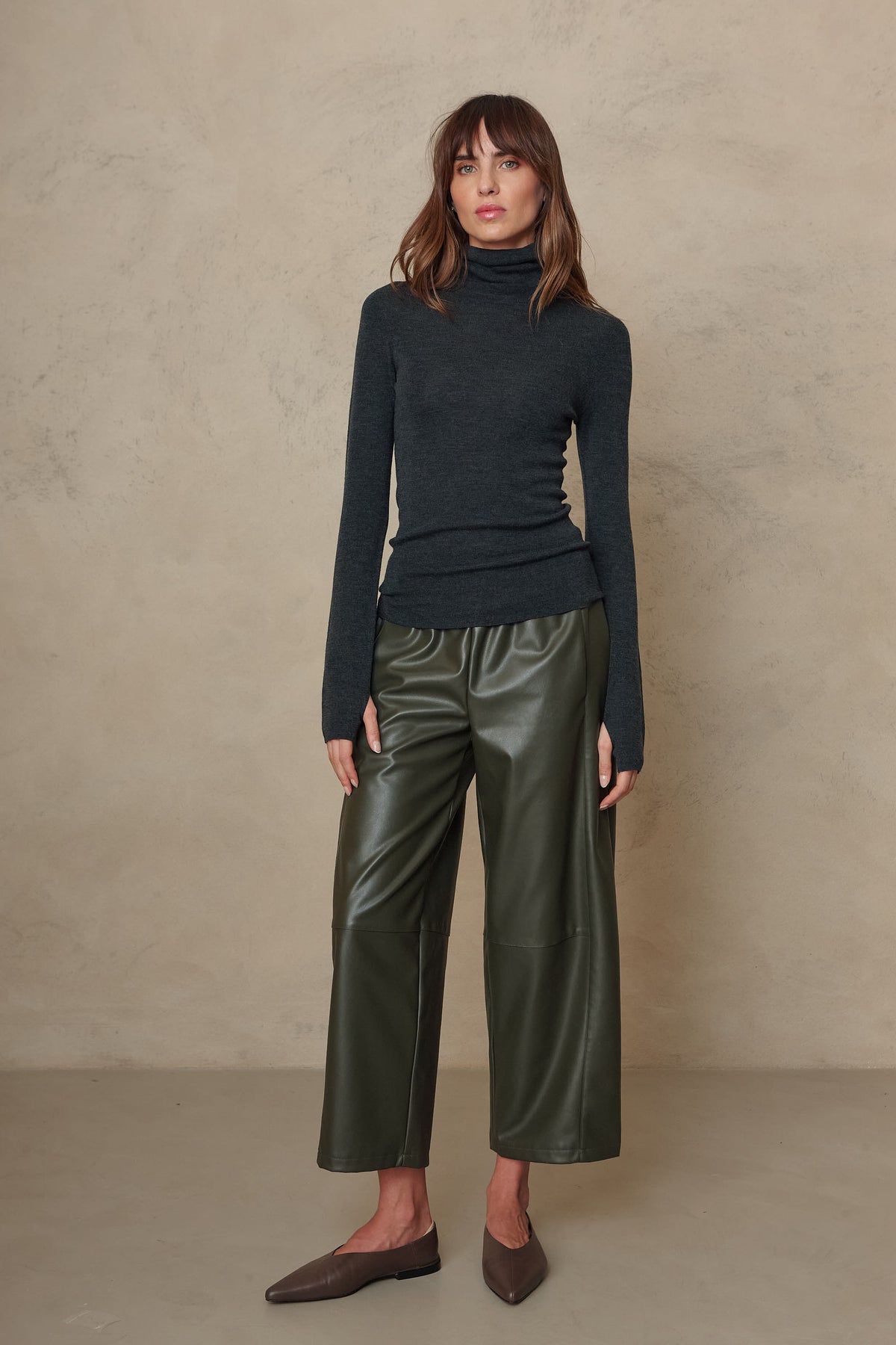 Gwyneth charcoal fine merino roll neck styled with olive faux leather trousers and brown loafers