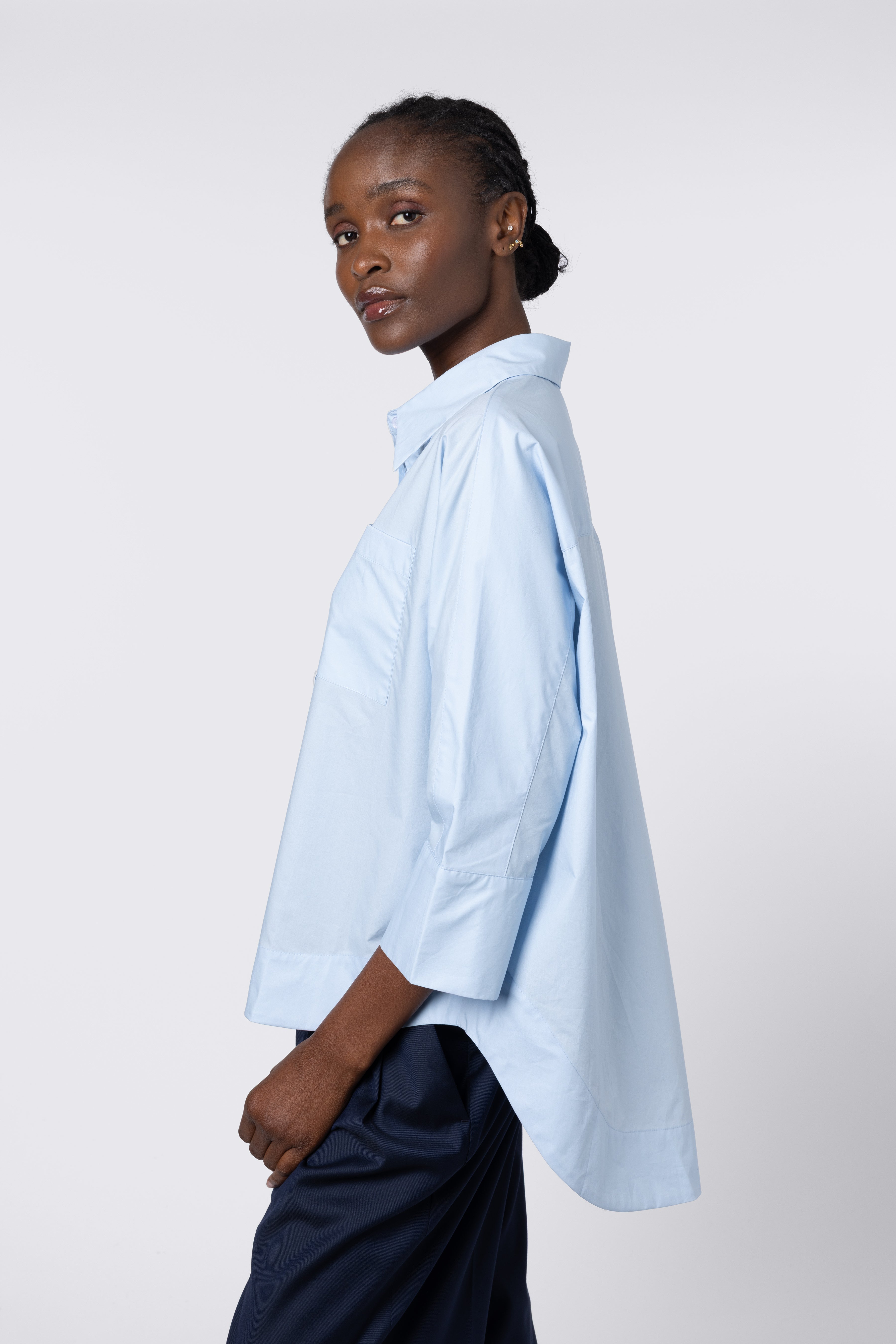 Woman wearing a light blue oversized shirt on a white background