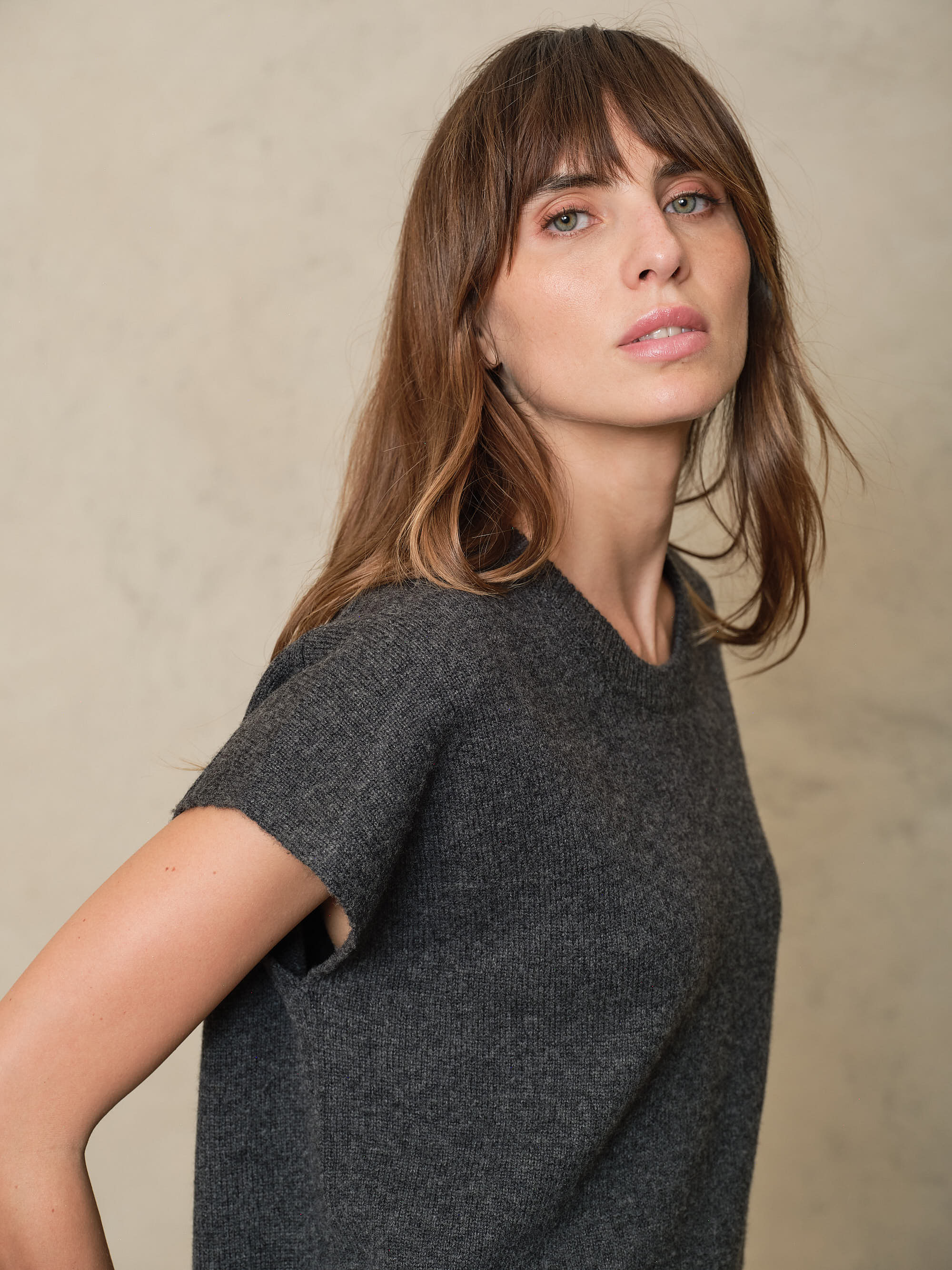Side view of the Ora charcoal knitted vest showing the dropped shoulder and cap sleeve