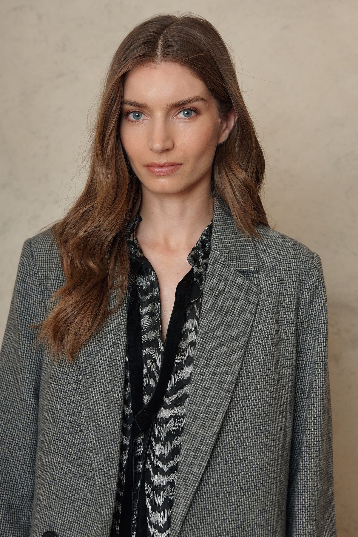 Close view of the houndstooth blazer lapel worn over a printed blouse