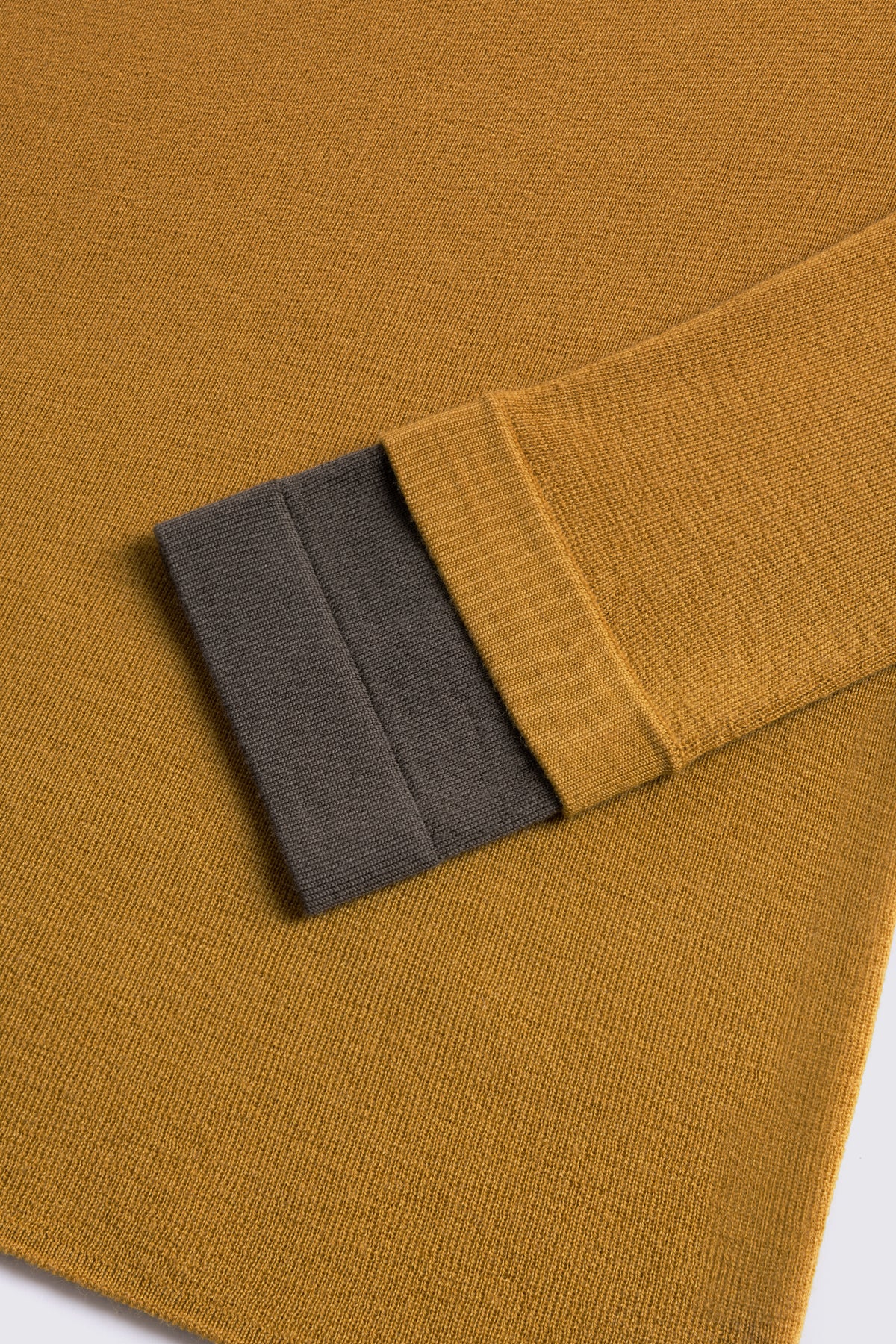Mustard merino crew neck jumper with a dark olive cuff, shown flat