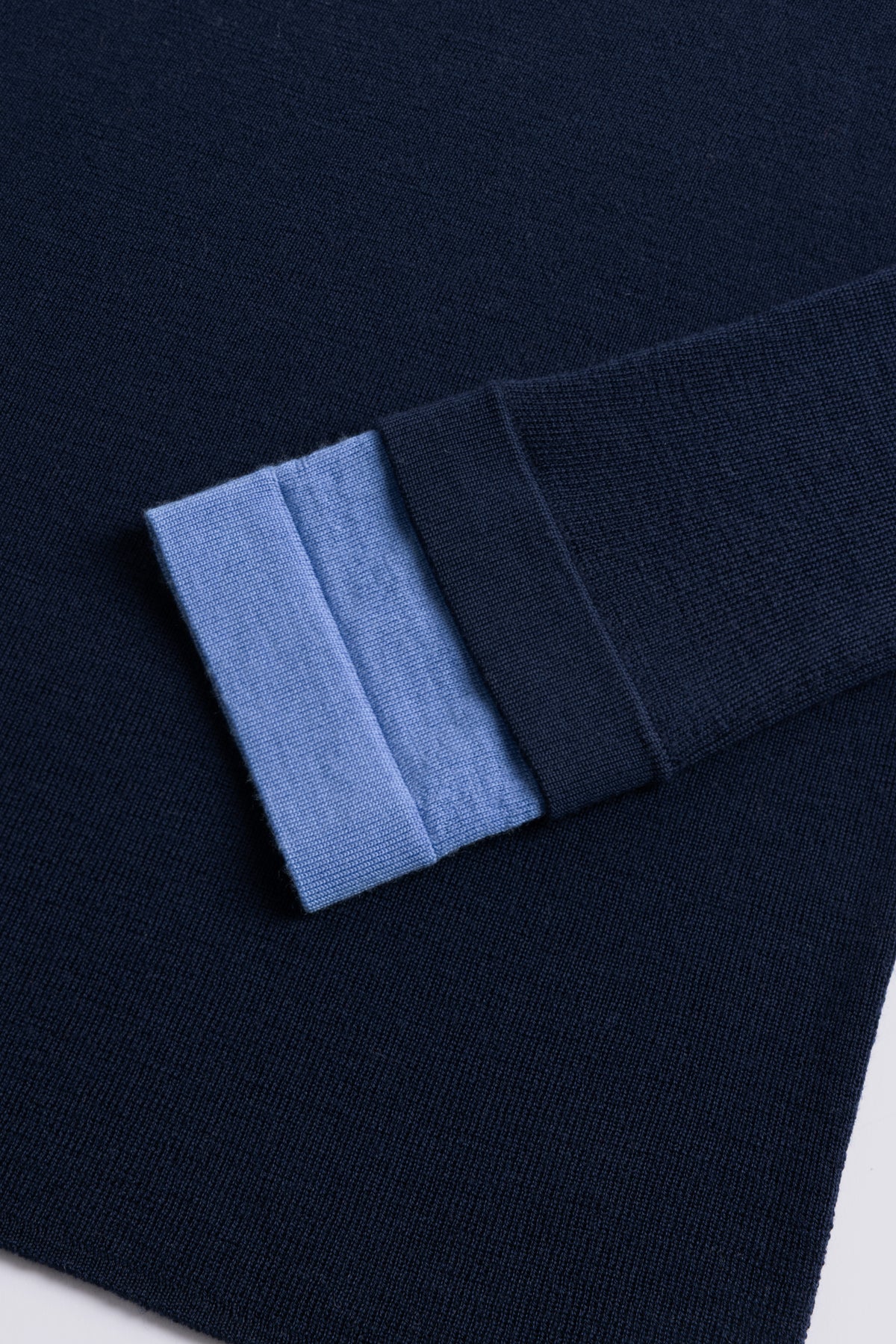 Navy merino crew neck jumper with a sky blue cuff, shown flat