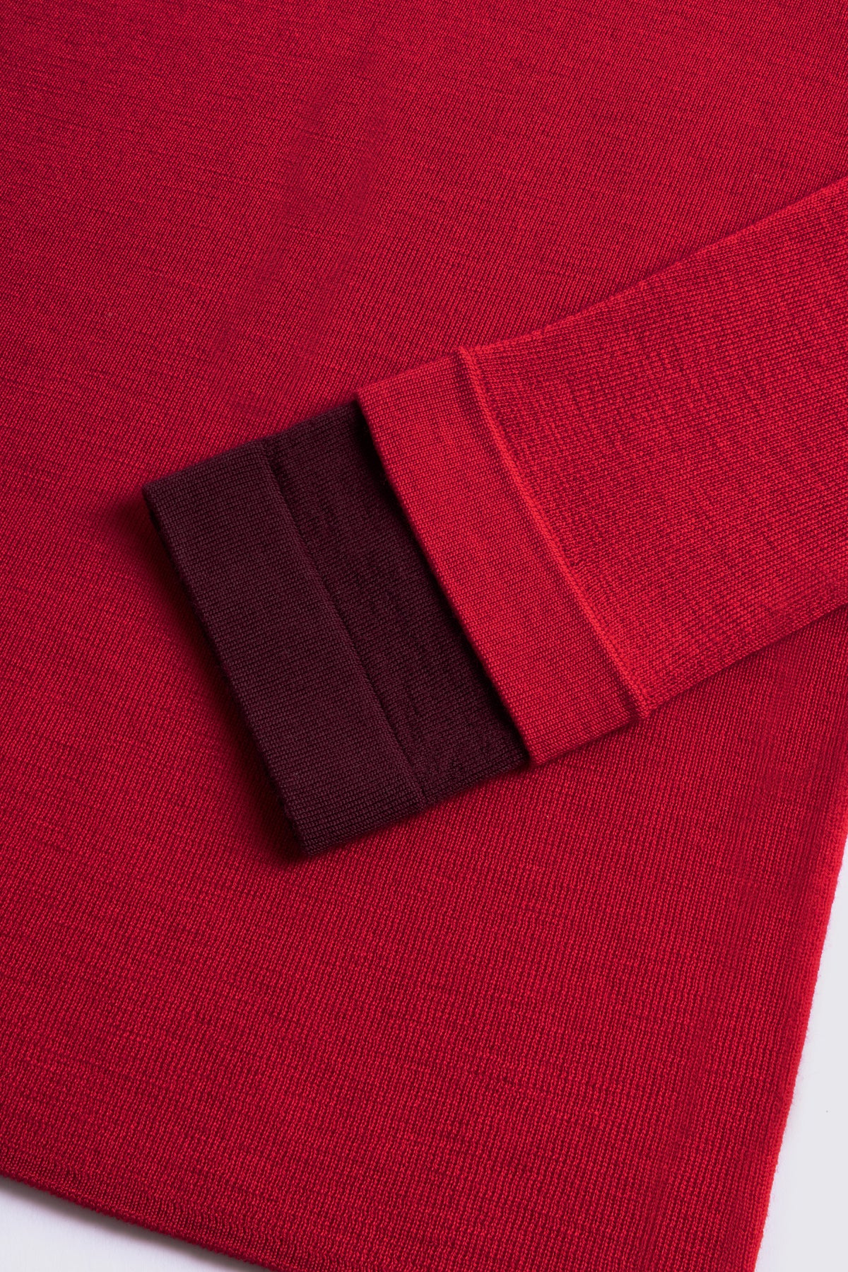 Red merino crew neck jumper with a burgundy cuff, shown flat