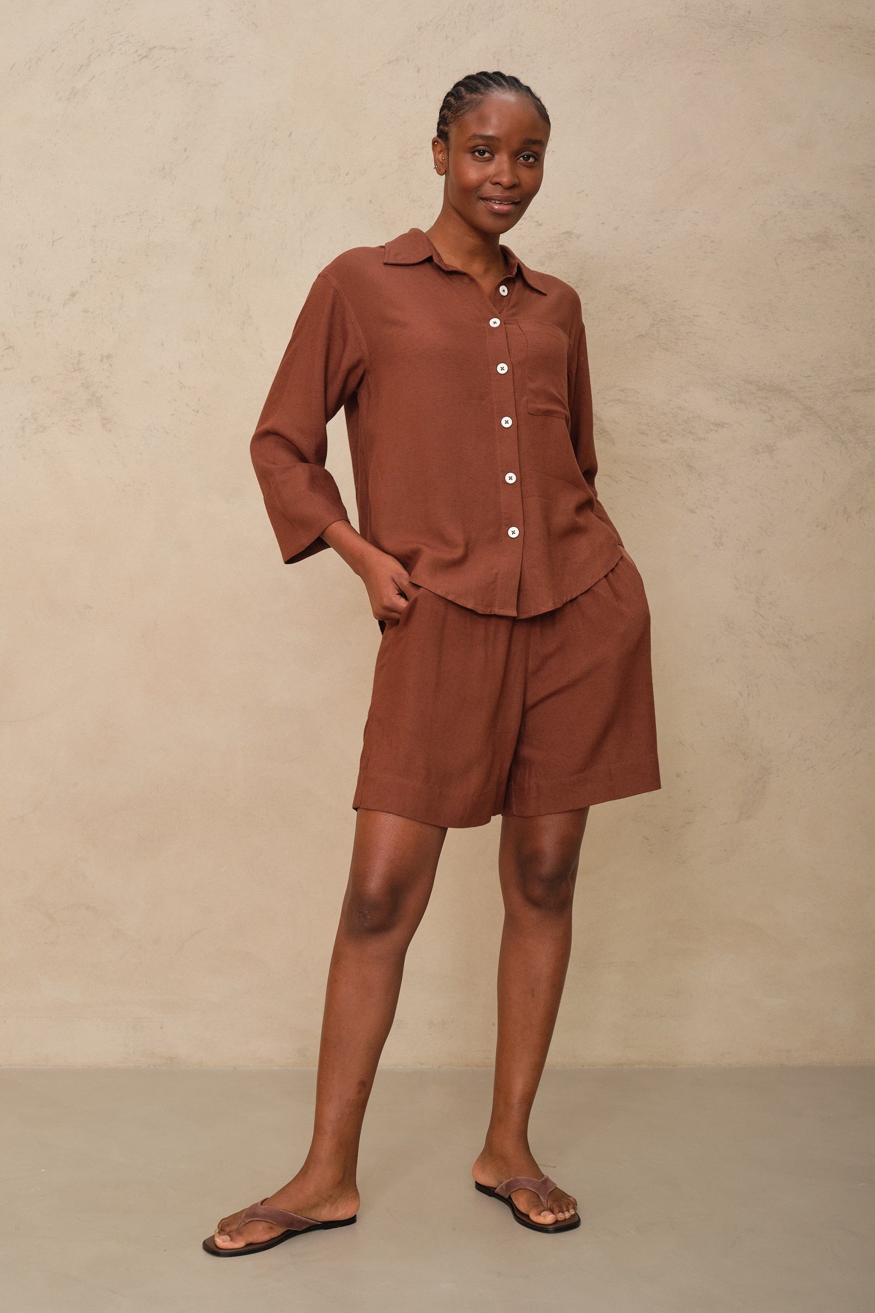 Woman wearing a brown outfit against a beige background
