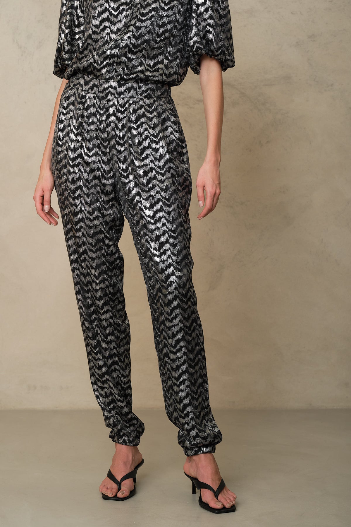 Close view of the silver trousers, showing the elasticated waist and soft drape