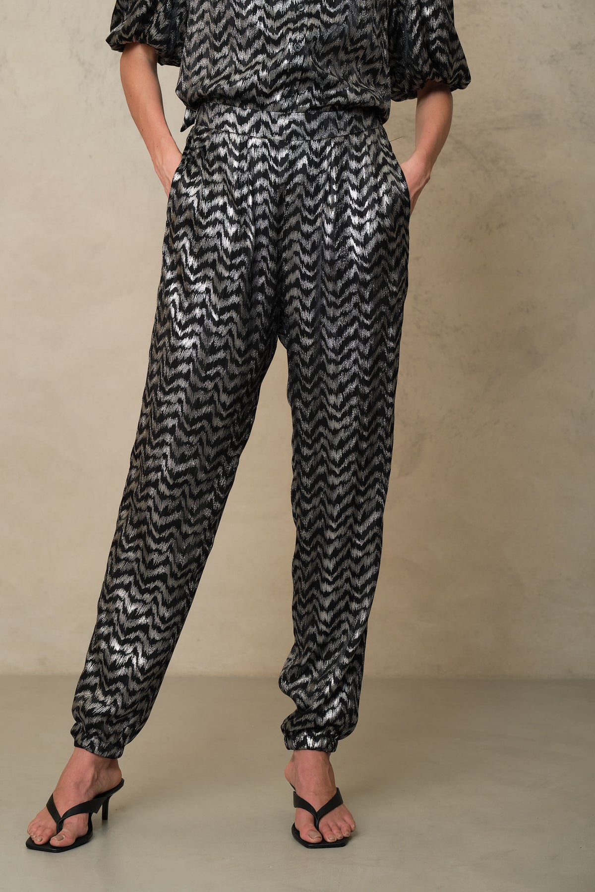 Silver print trousers worn with the matching metallic blouse and black sandals