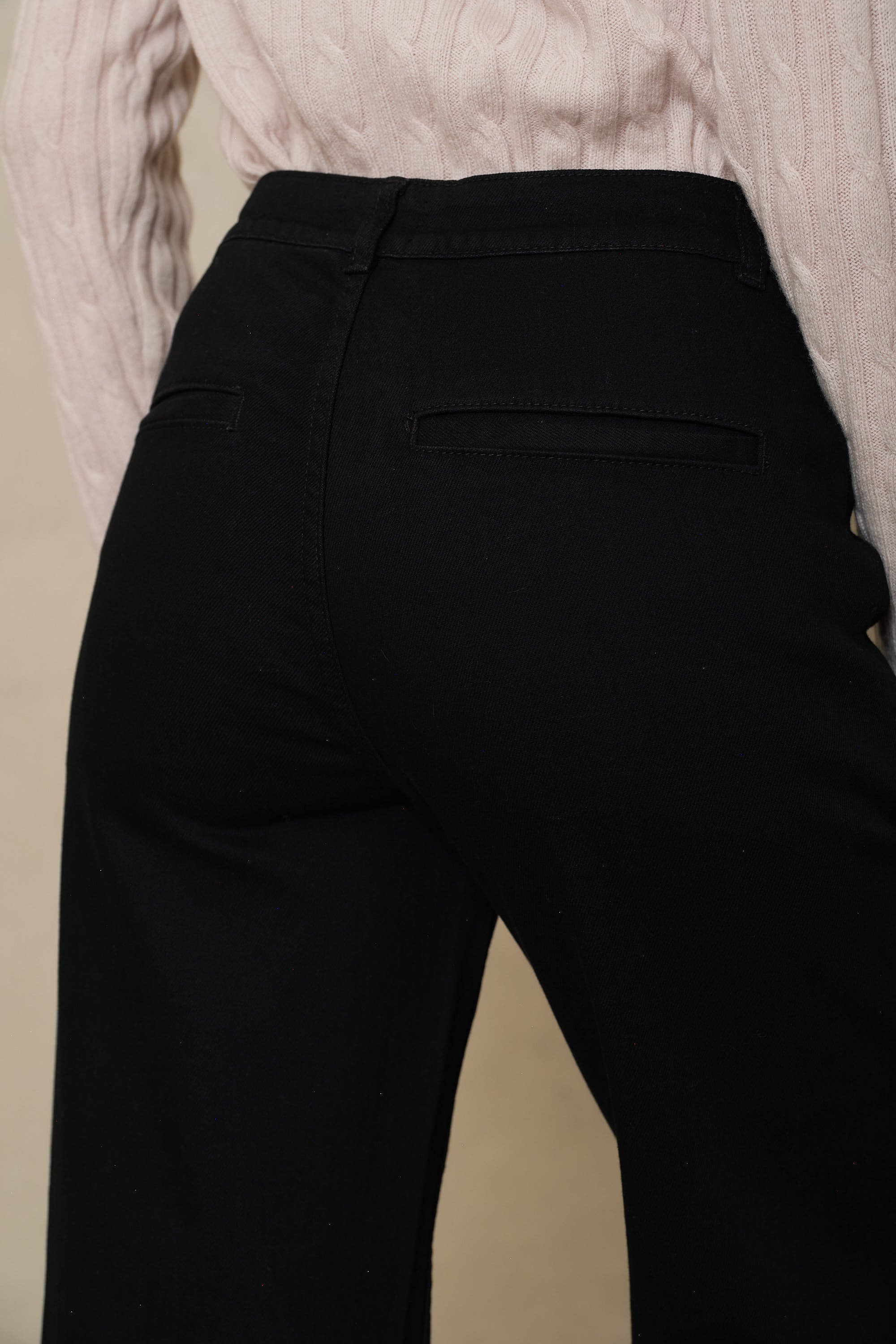 Close back detail of the black wide leg jeans, showing the high waistband and welt pockets