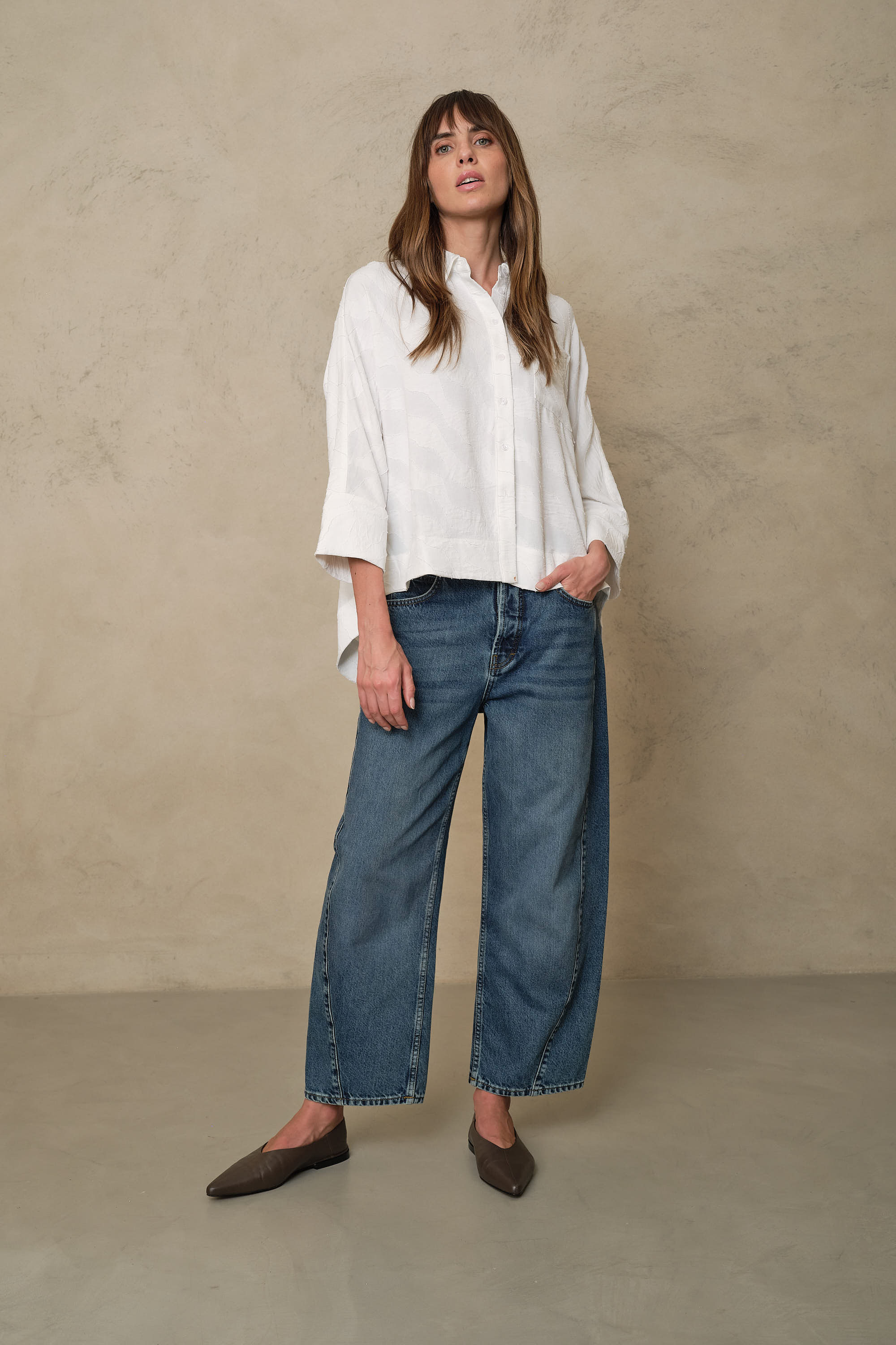 Rosie mid wash twist front jeans worn with an ivory oversized shirt and brown flats