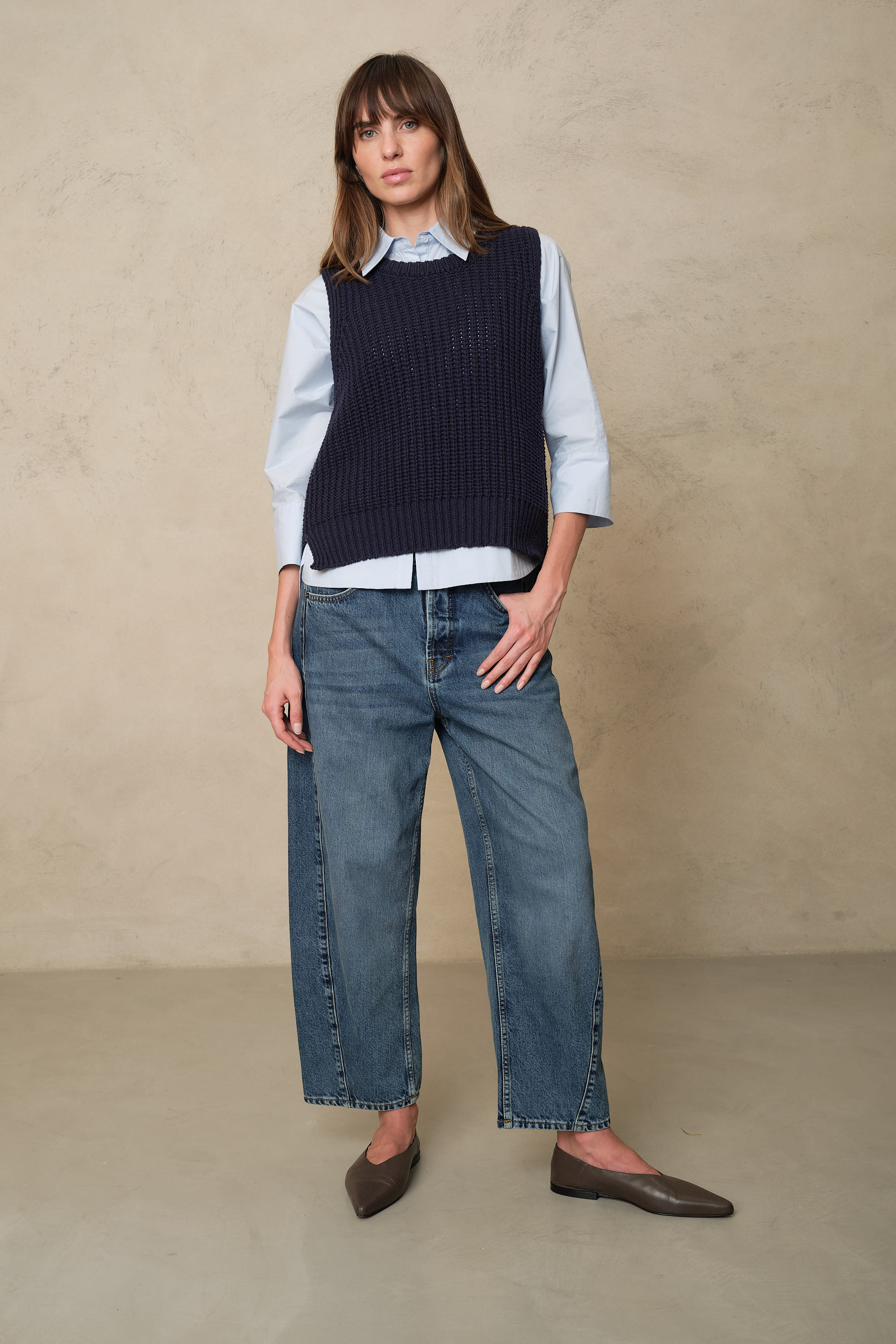 Rosie mid wash twist front jeans layered with a pale blue shirt and a navy knitted vest