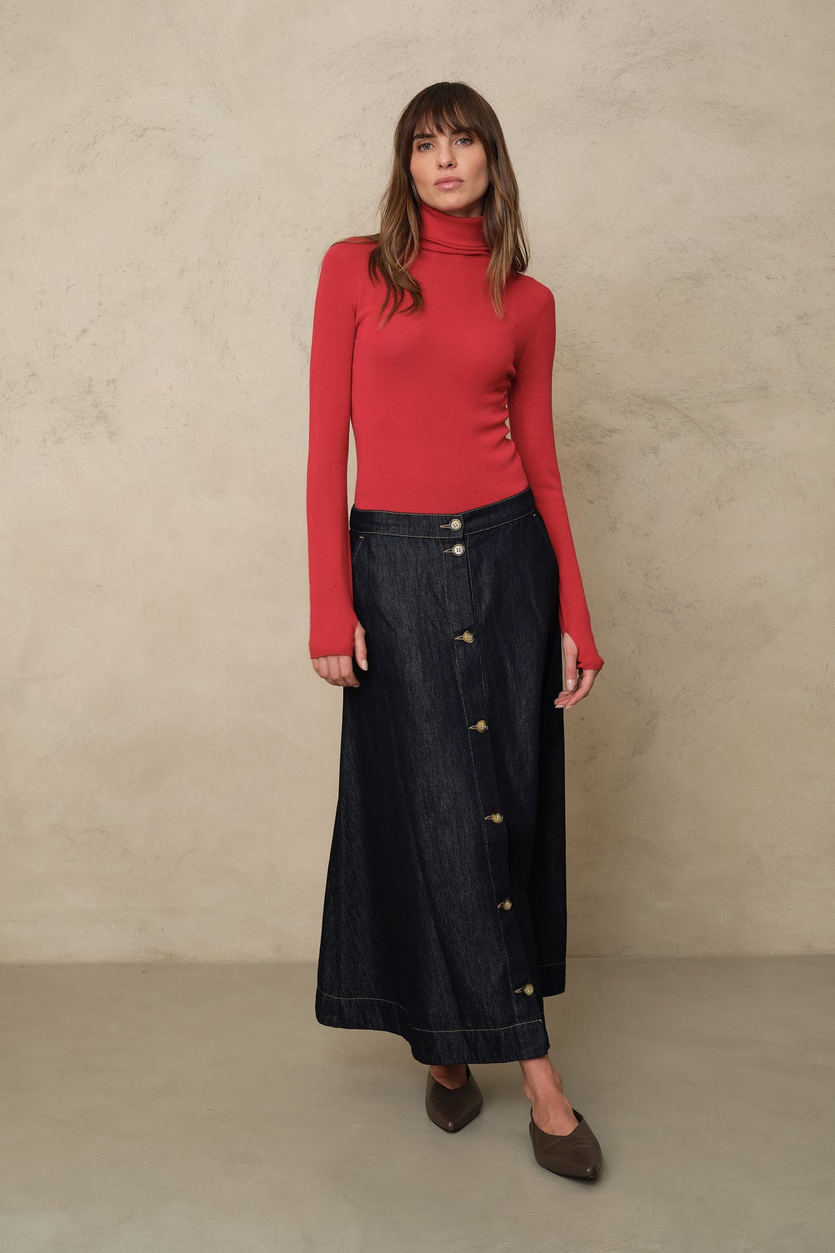 Gwyneth roll neck in red styled with a denim midi skirt and flats, walking