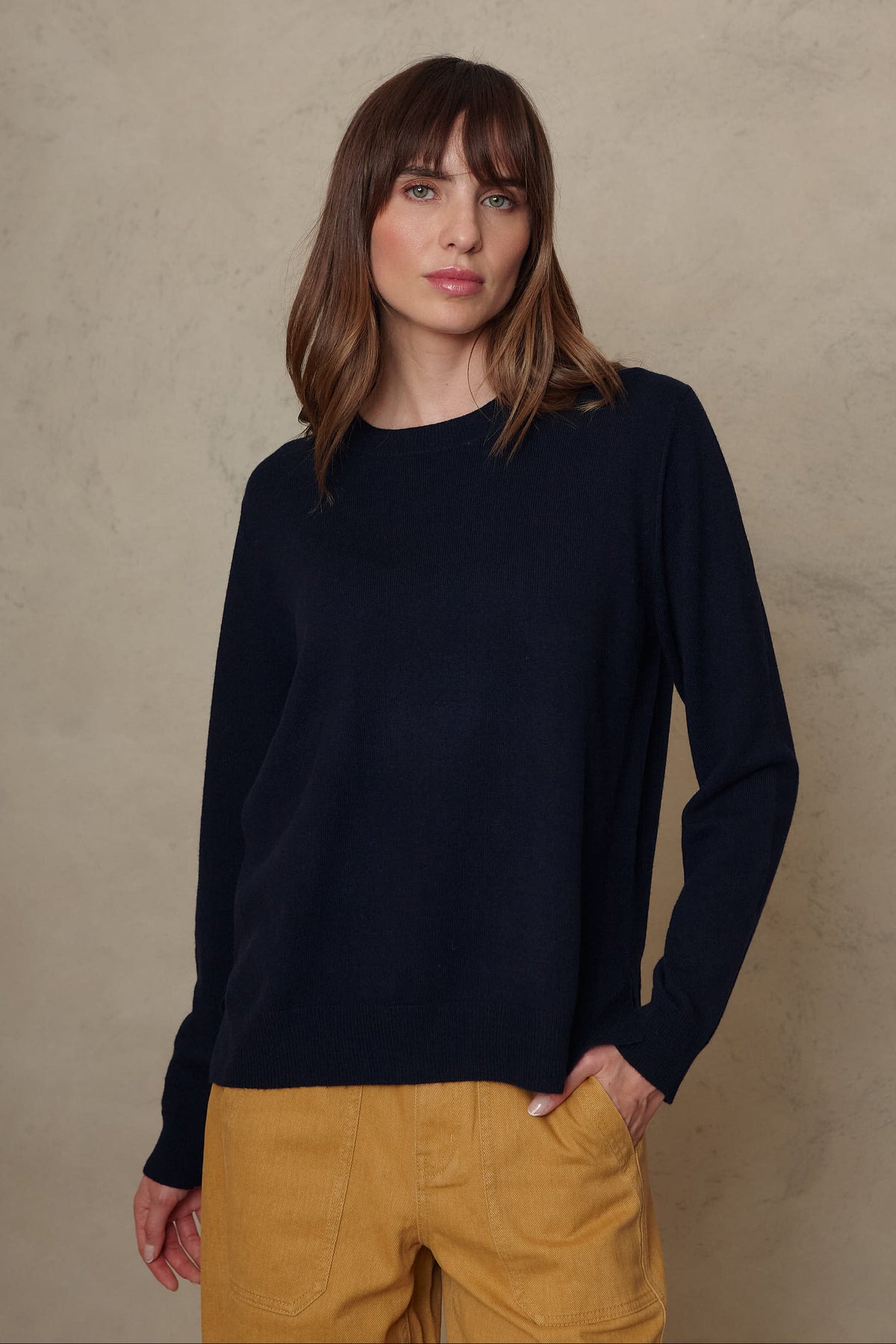 Alex cashmere blend jumper in navy worn with mustard trousers, hands in pockets
