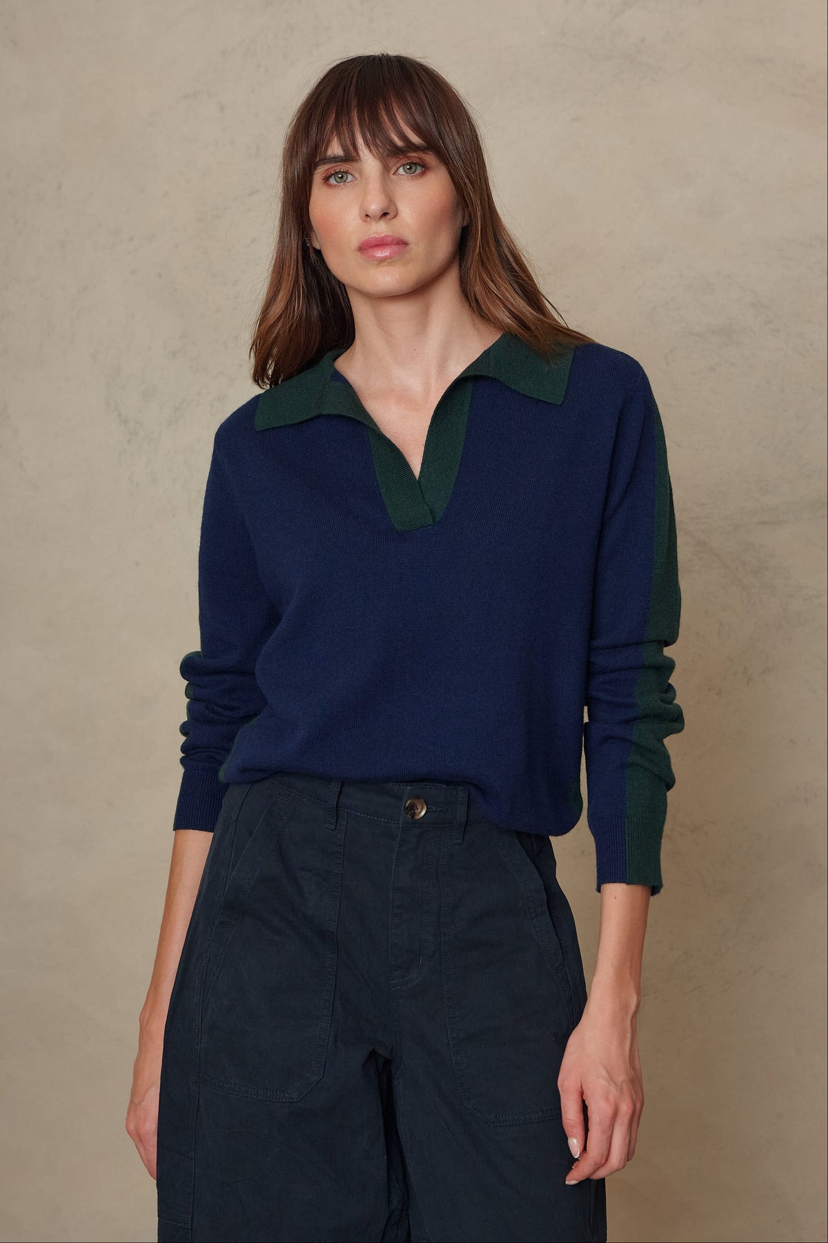 Model wearing the Tria notch collar jumper in navy with a contrast green collar, front view