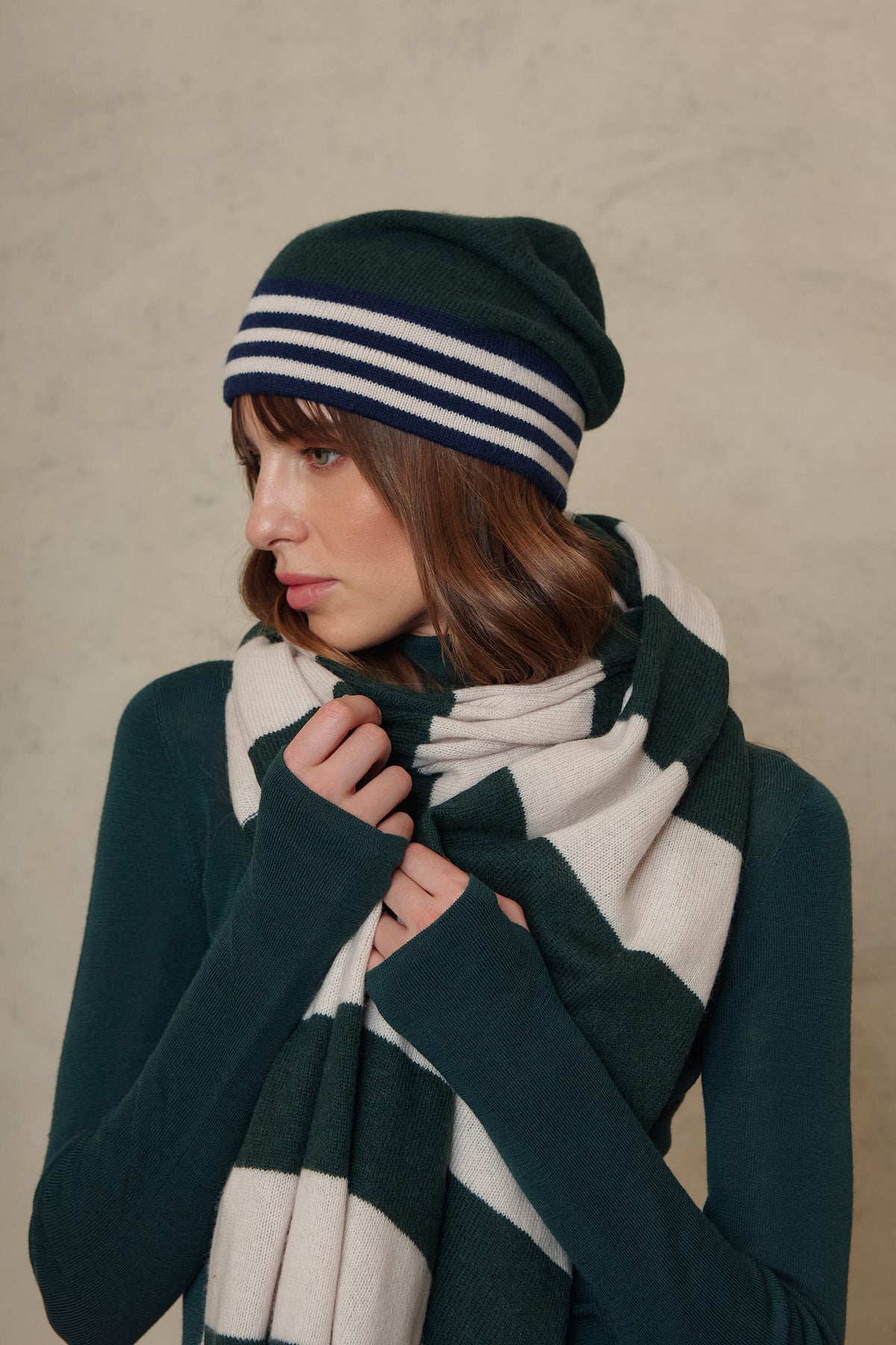 Side profile of the Carmel cashmere blend scarf in soft stone and bottle green, wrapped high at the neck