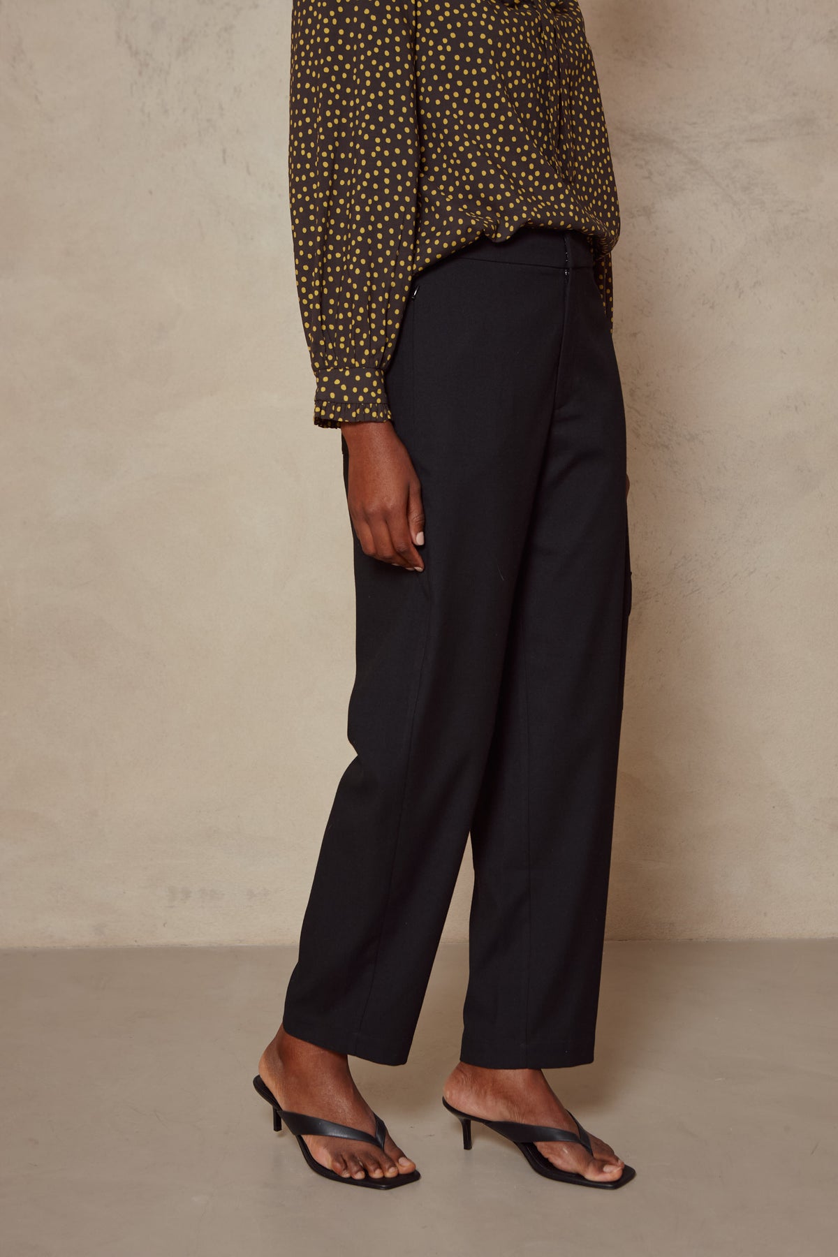 Side view of the Tess clean cargo trousers in black, showing the cropped ankle length