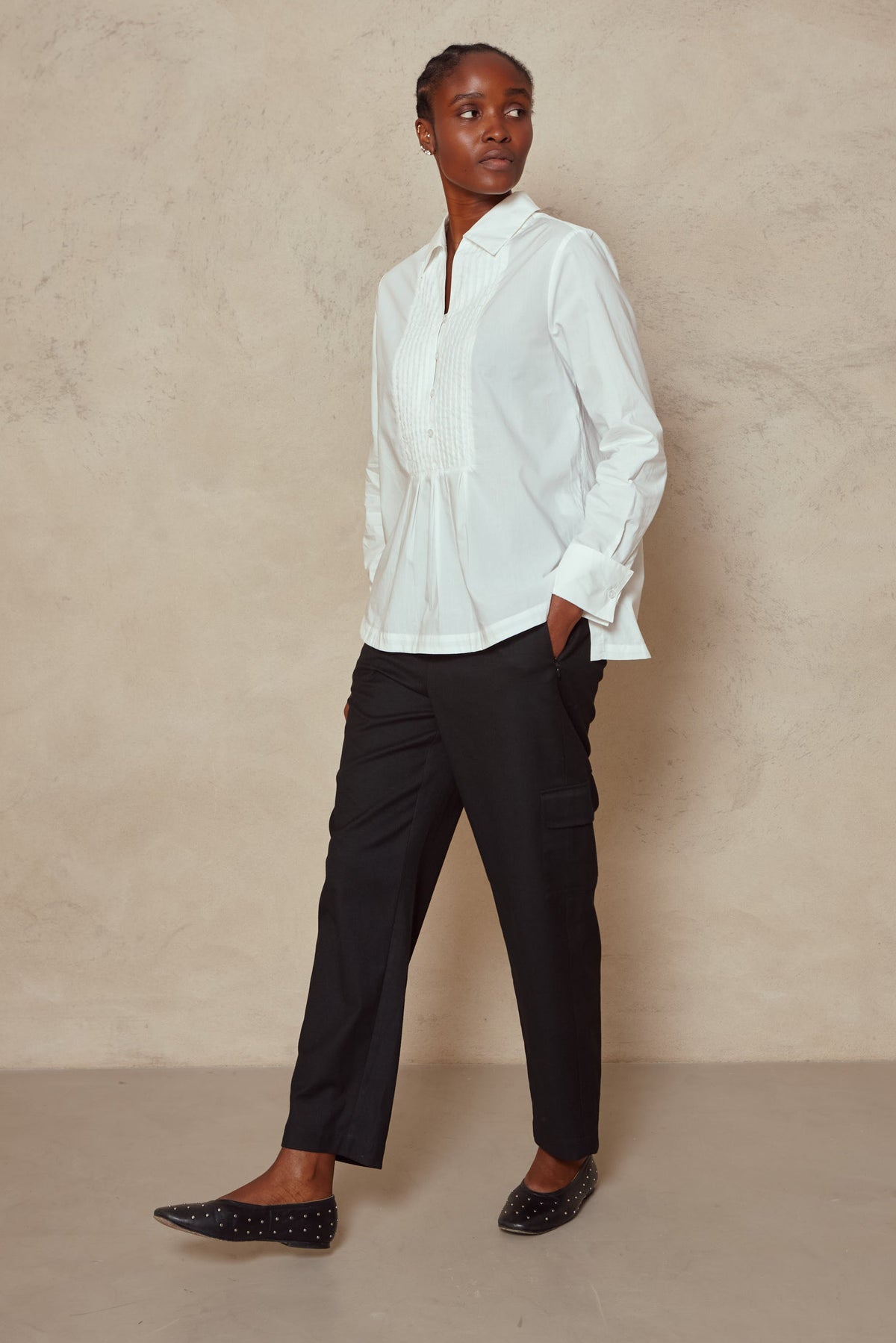 Model wearing the Tess clean cargo trousers in black with a white shirt and black flats