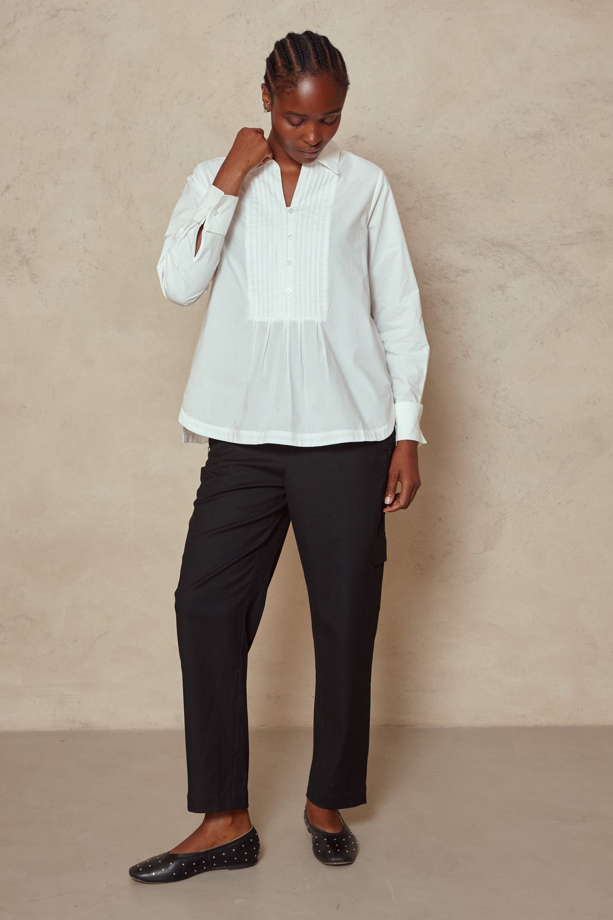 Full length view of the Etta ivory bib shirt worn loose with black trousers and flats