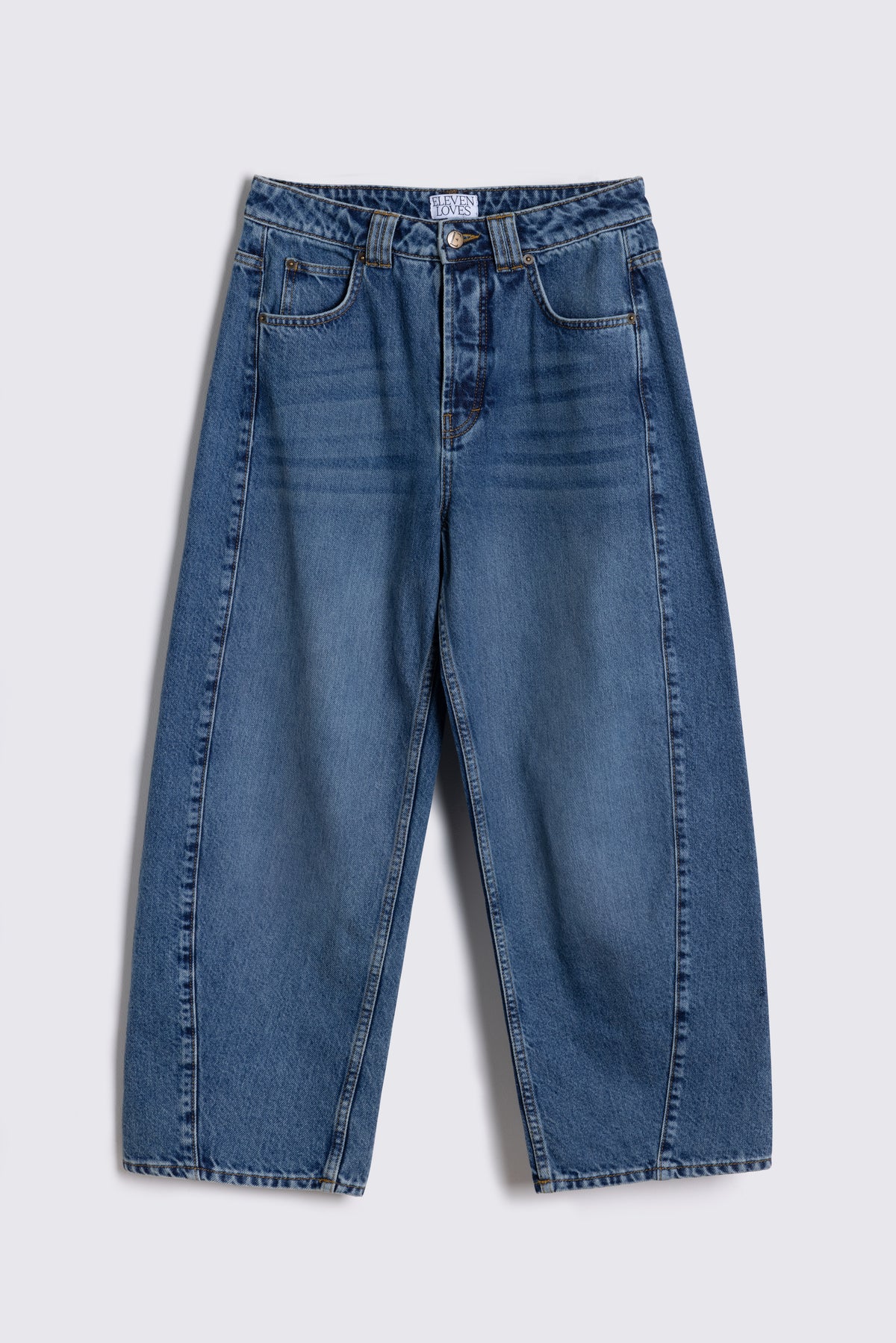 Rosie twist front jeans in mid wash, showing the curved leg, on a plain background