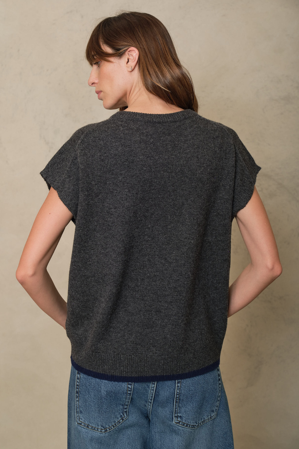 Ora charcoal knitted vest showing the dropped back hem and navy trim, back view