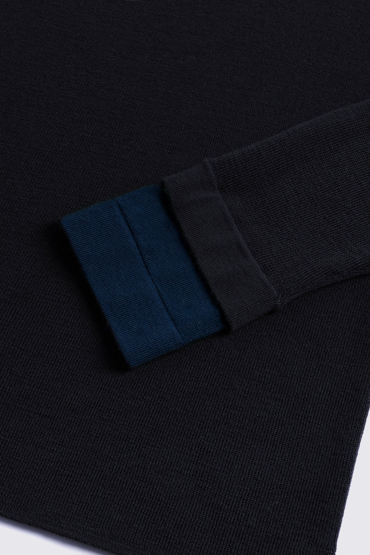 Black merino crew neck jumper with a navy cuff, shown flat