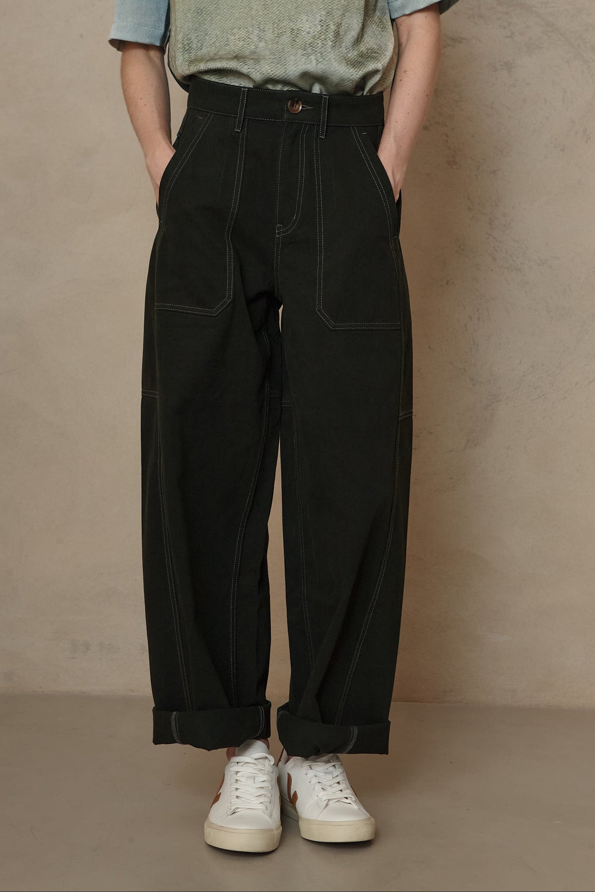 Billie barrel leg trousers in forest green with contrast stitching and a sage top, front view