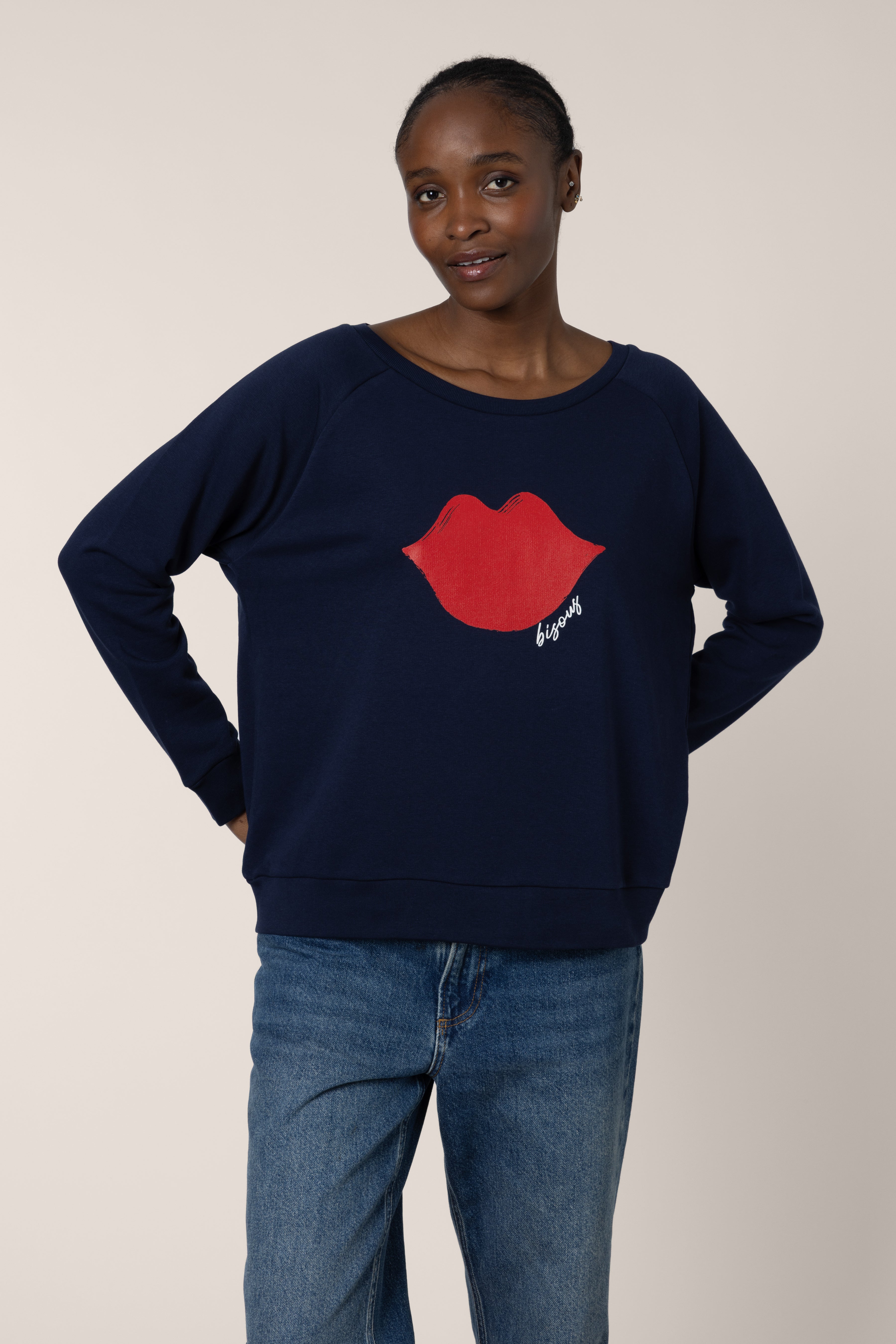 Person wearing a navy blue sweater with a red lip design on a plain background