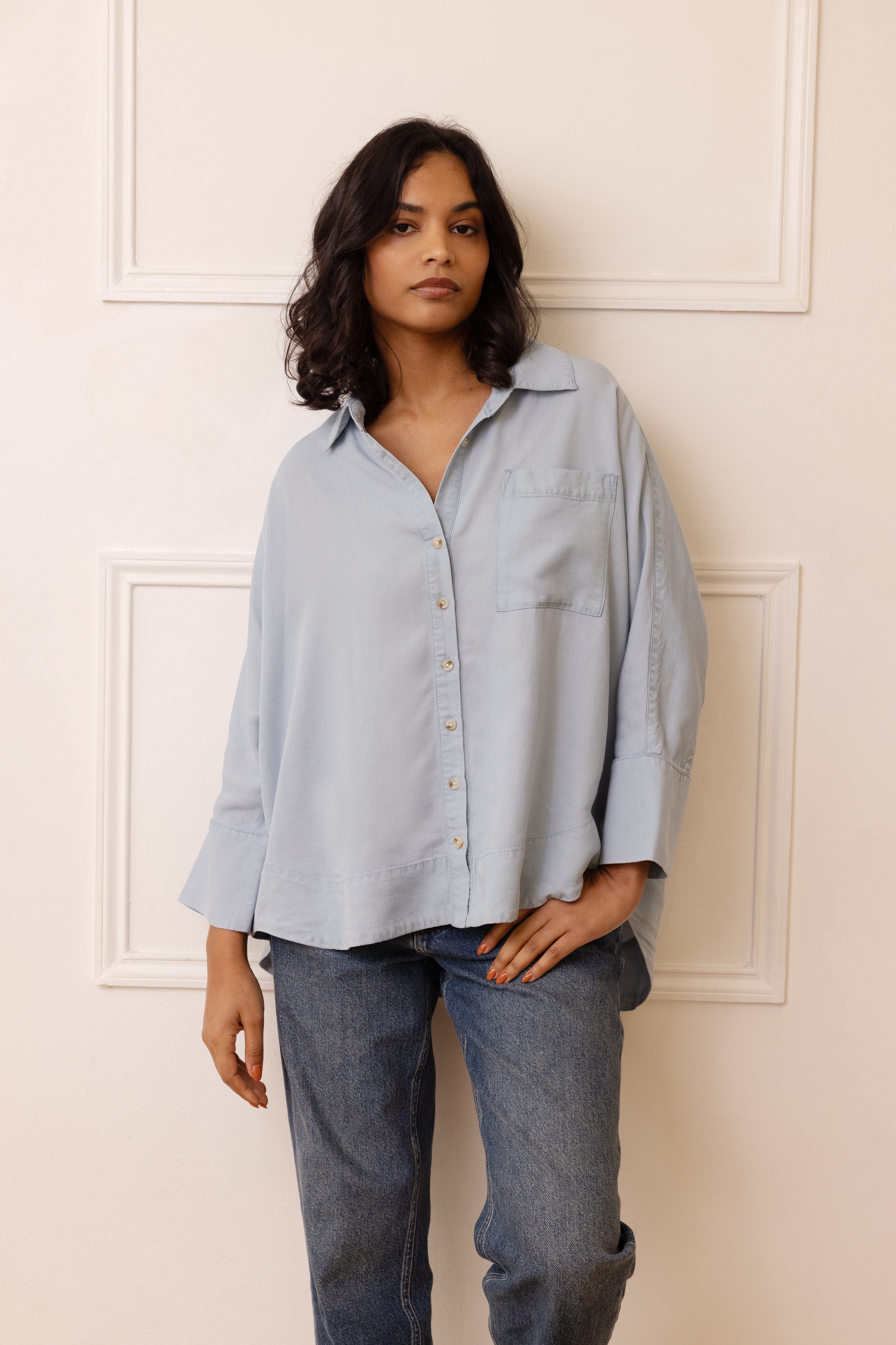 Front view of woman wearing oversized blue chambray shirt.
