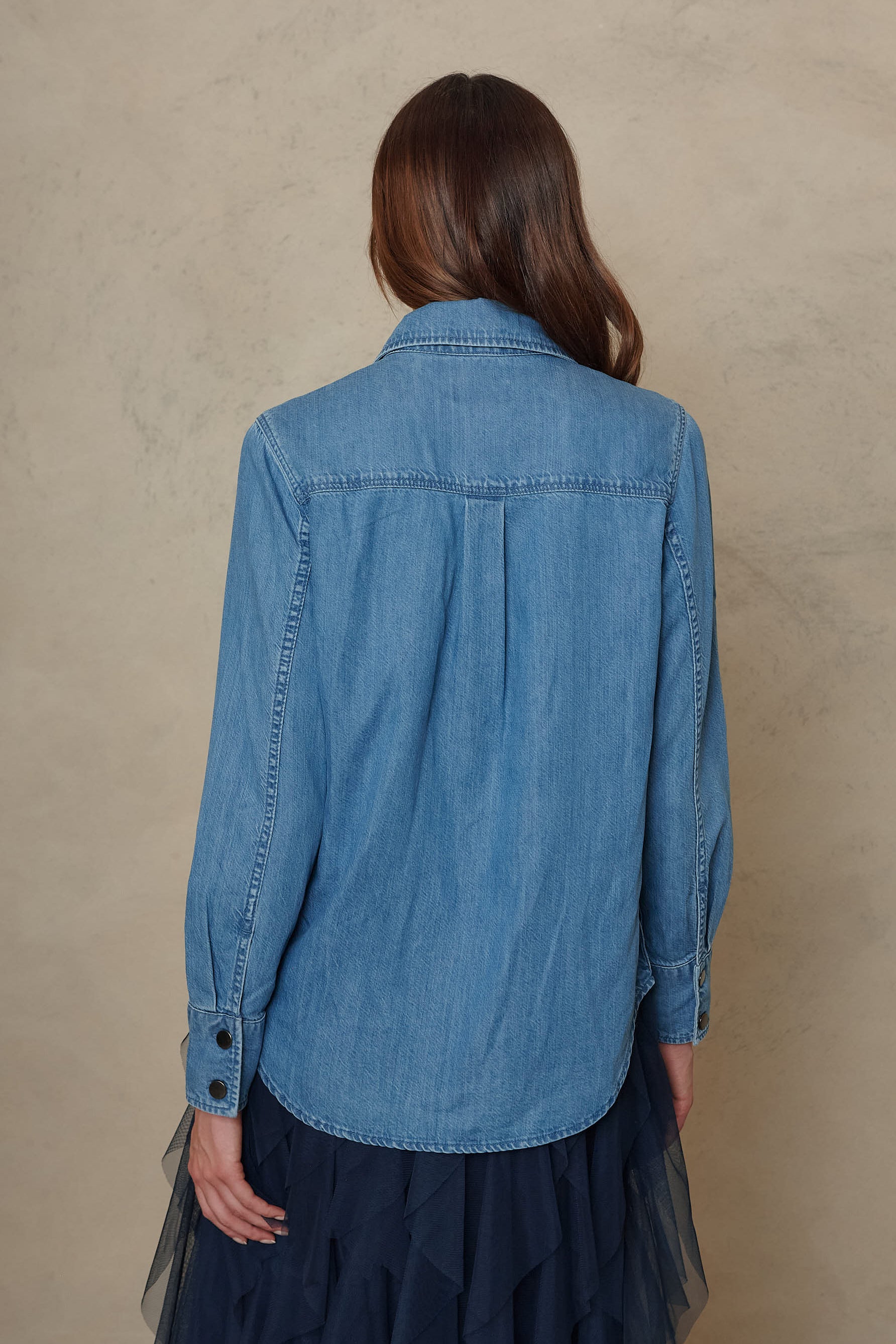 Joni mid wash denim shirt showing the back yoke and curved hem, back view