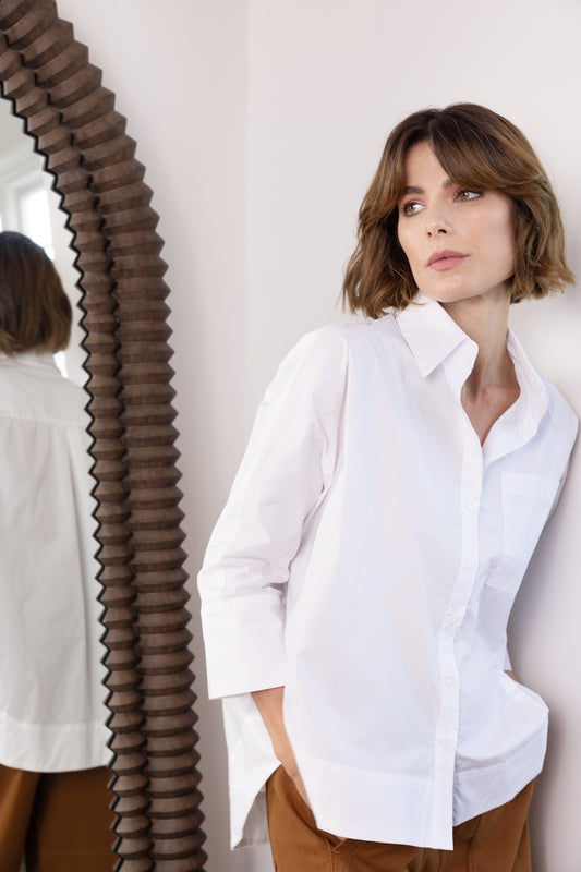 model wearing white cotton shirt next to mirror