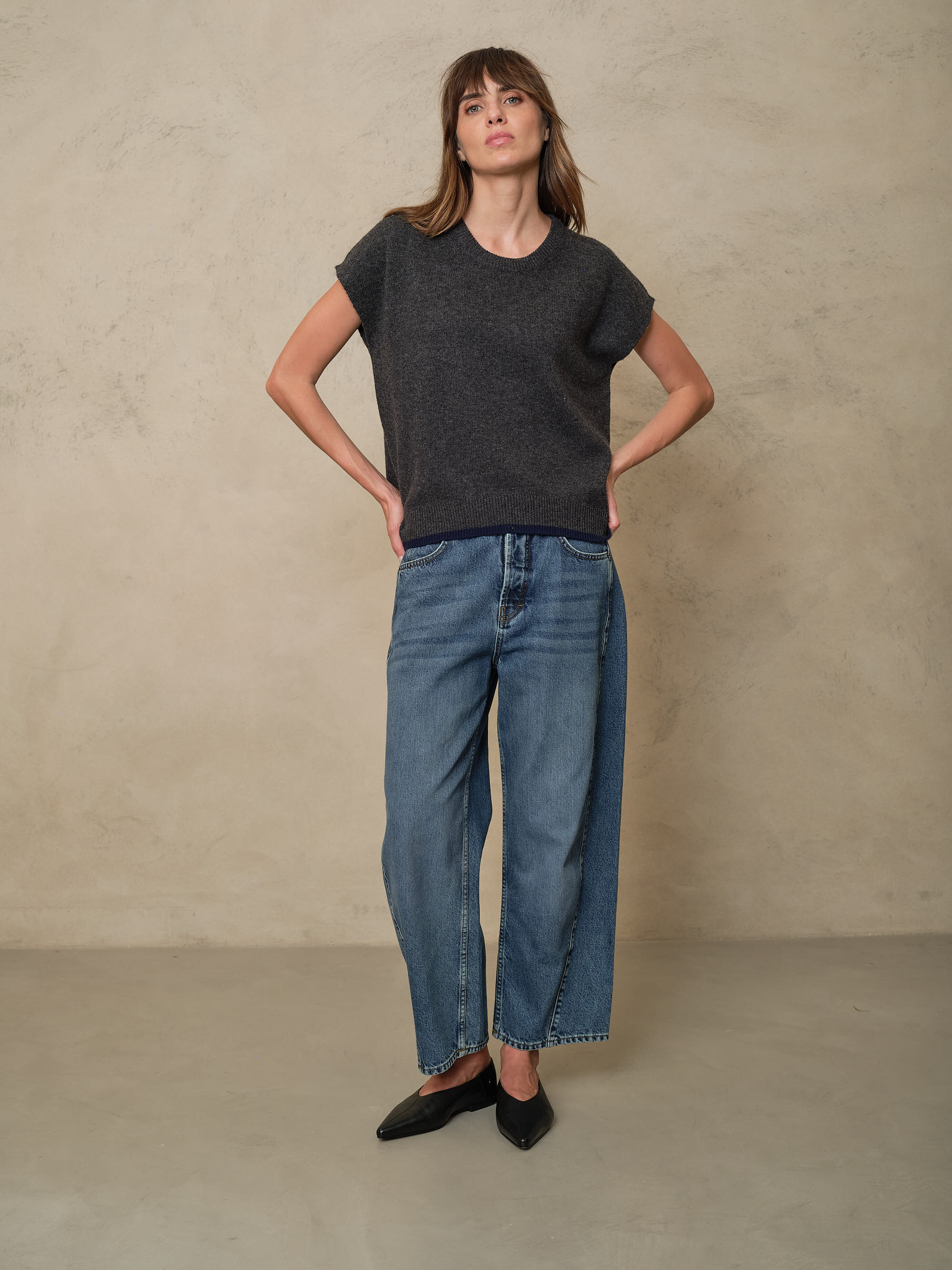 Full length view of the Ora charcoal knitted vest worn with the Rosie Twist Front Jeans in mid wash