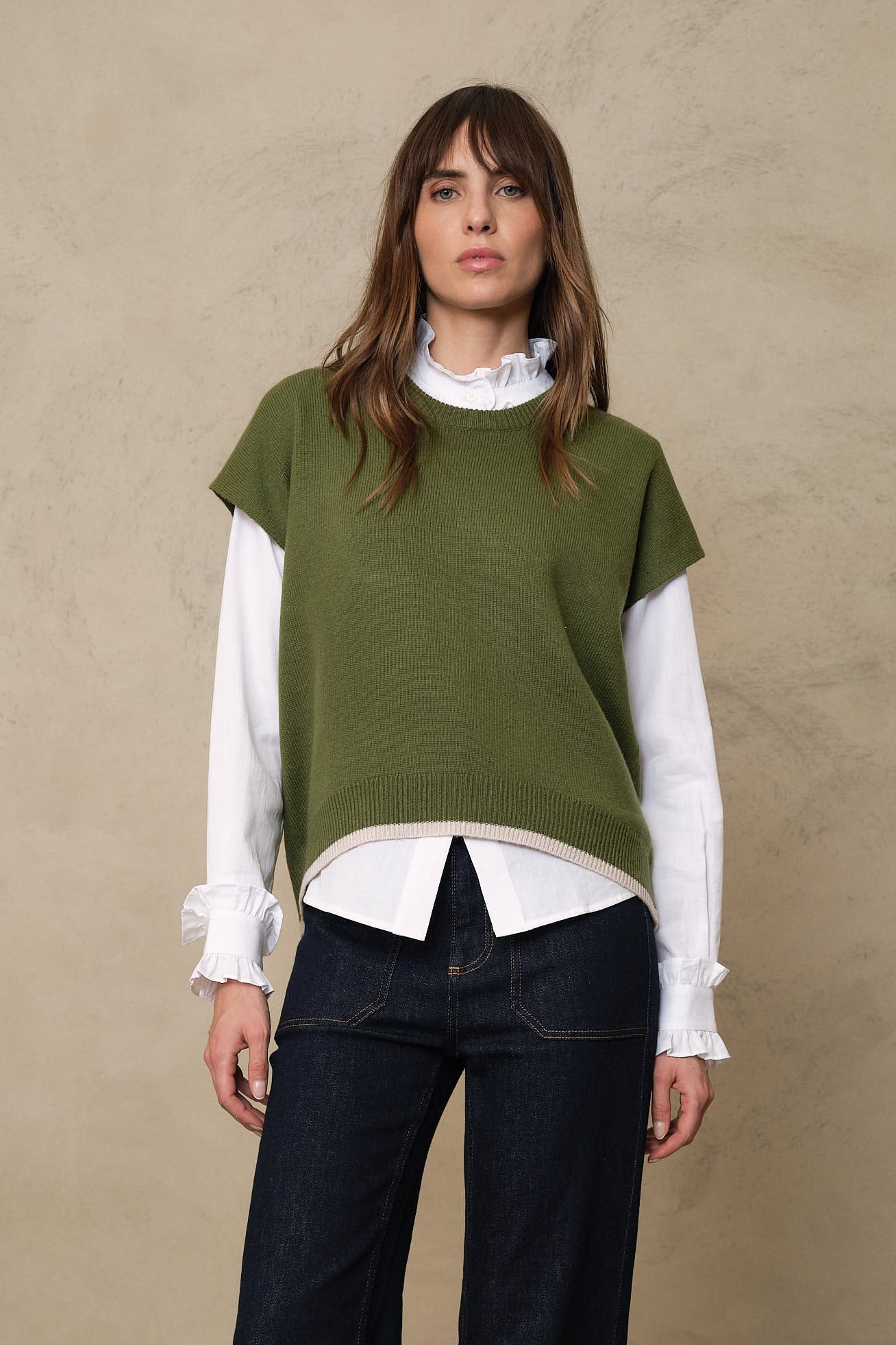 Posy ruffle collar shirt layered under the Ora knitted vest in light olive, with the frill collar and cuffs showing