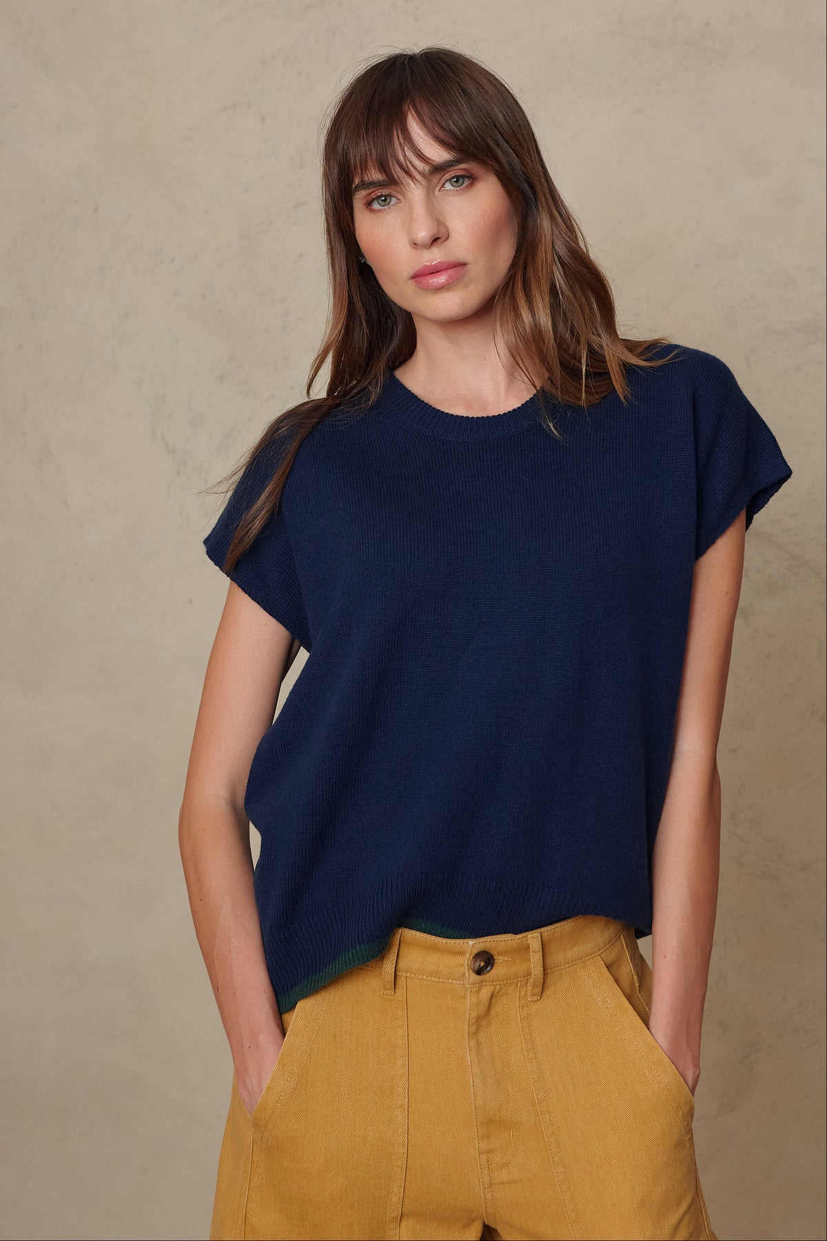 Ora cashmere blend tank in navy tucked into mustard trousers, side angle