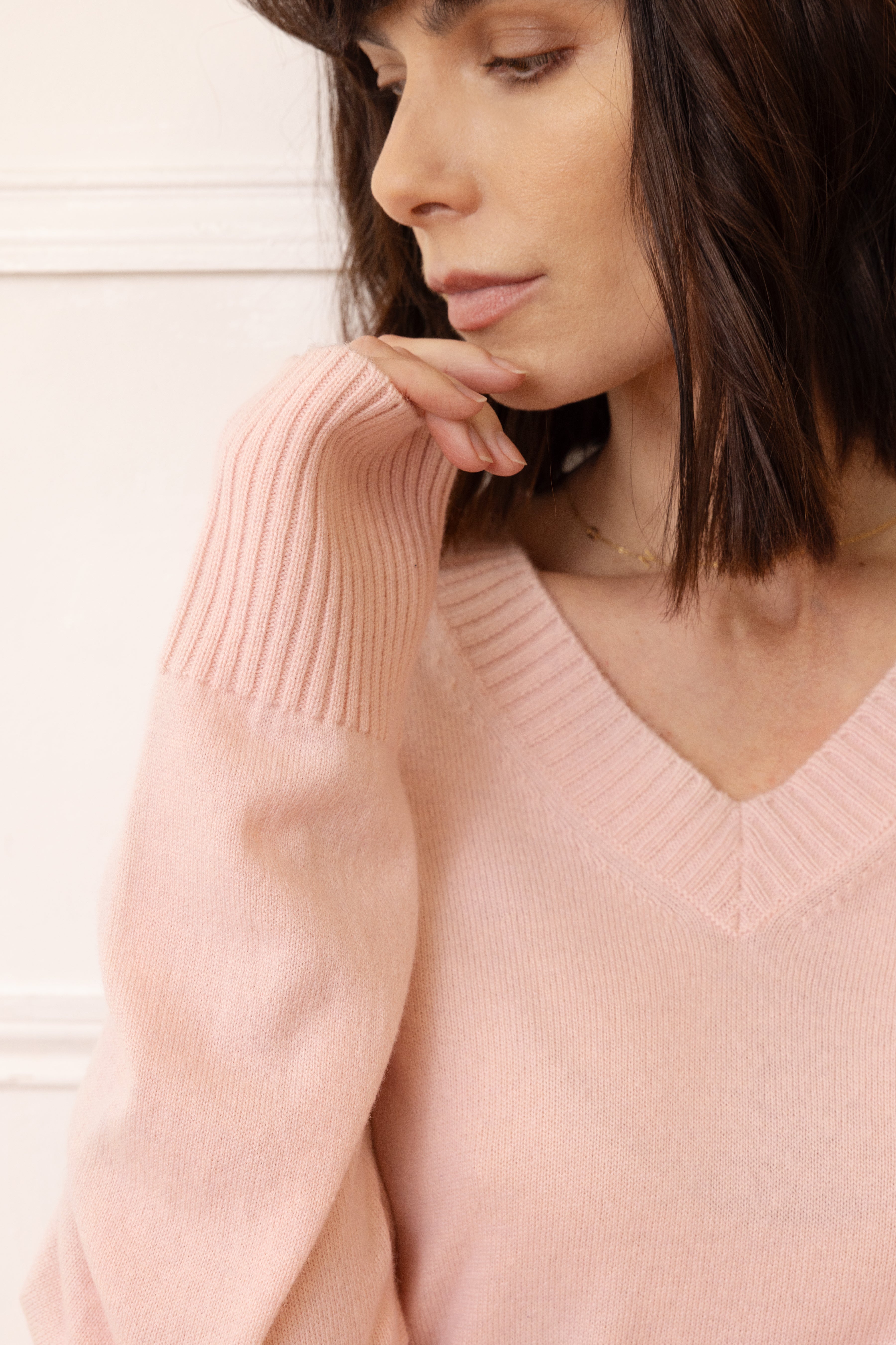 Woman wearing a pink sweater against a light background