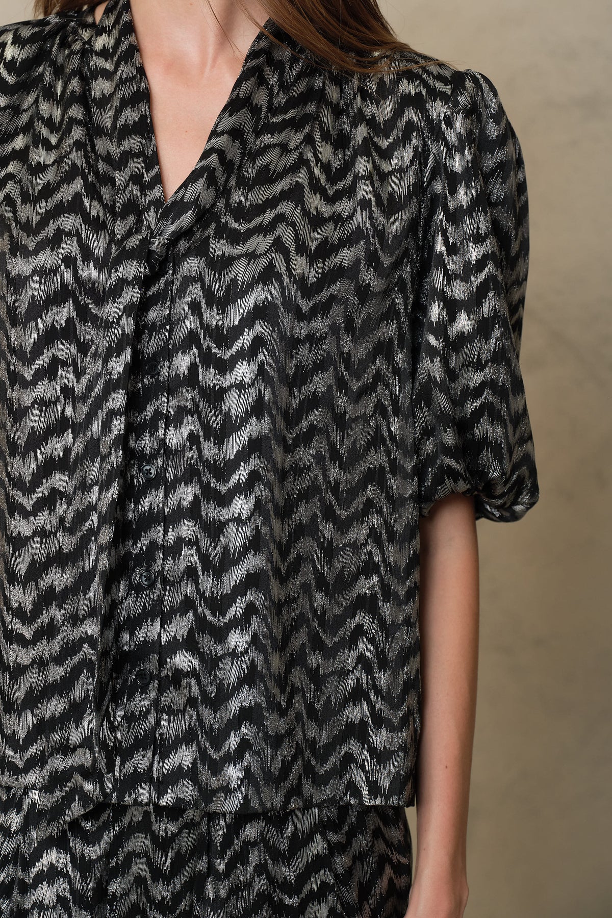 Close up of the Poppy silver stripe blouse showing the metallic zigzag print and tie neck