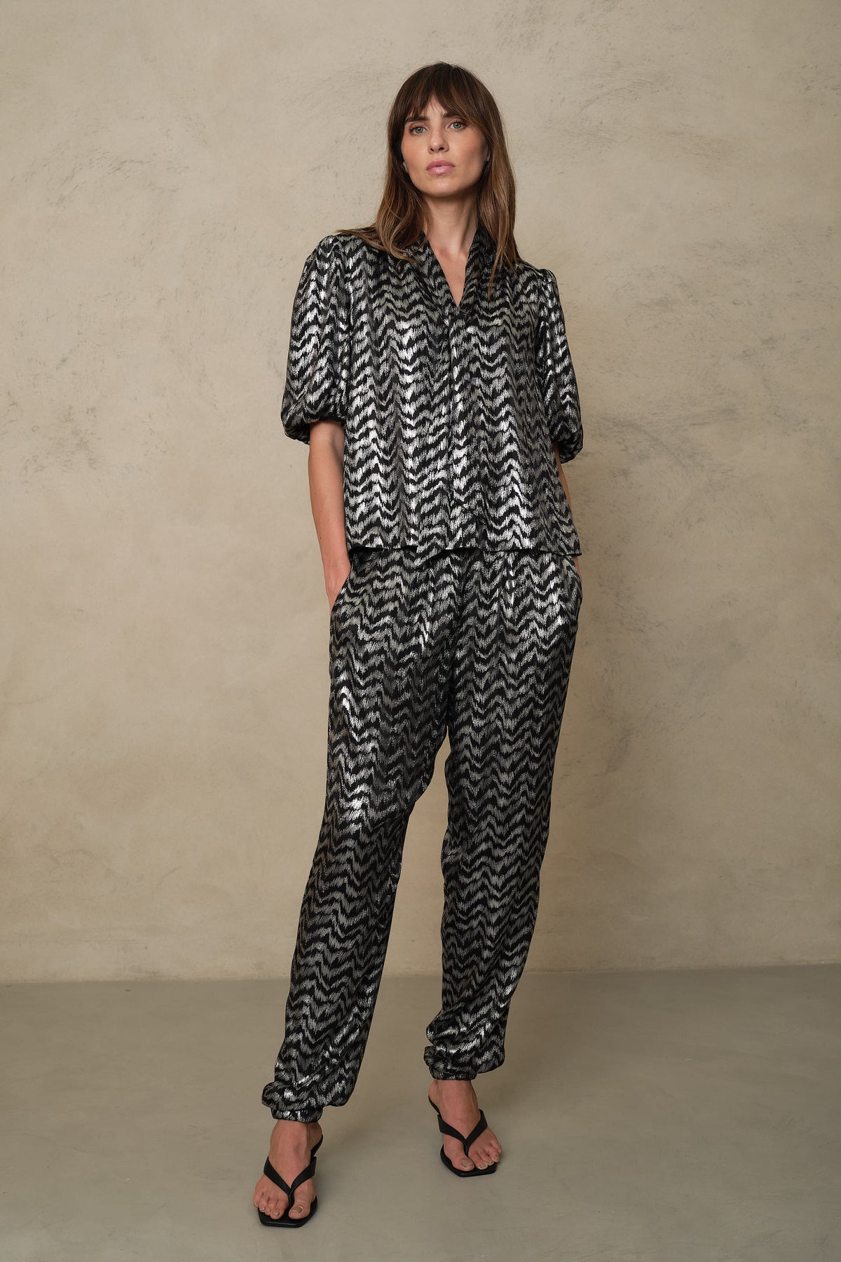 Full length three quarter view of the Poppy blouse in silver stripe with matching trousers