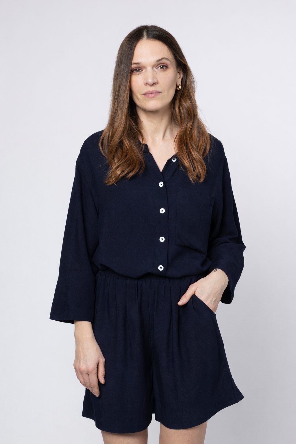 Woman wearing a navy blue romper with a plain background