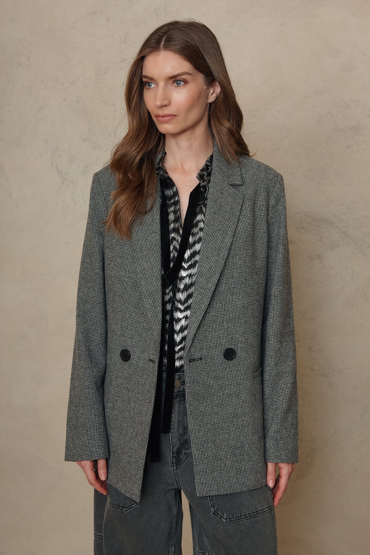 Houndstooth blazer worn open over a black and white printed blouse with denim