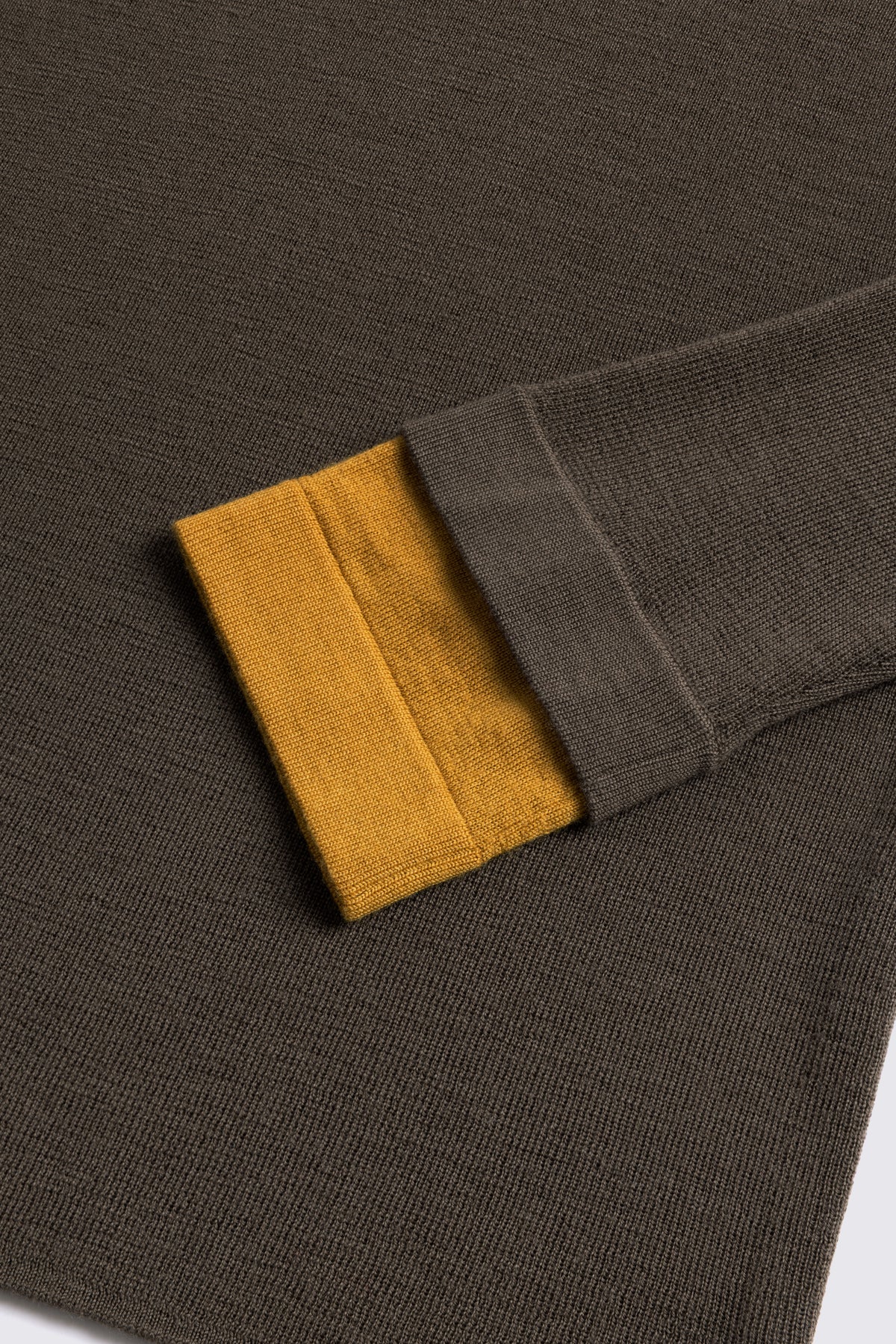 Dark olive merino crew neck jumper with a mustard cuff, shown flat