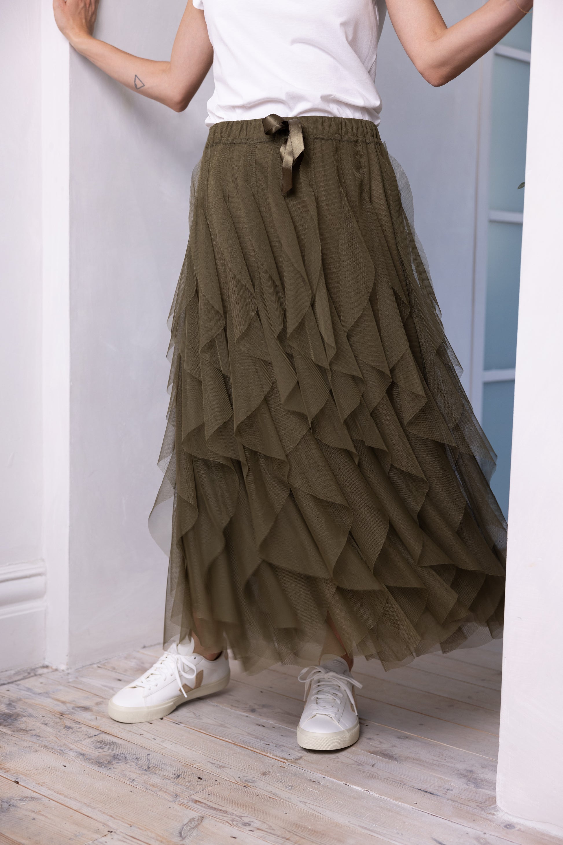 model wearing olive tulle maxi skirt in a hallway